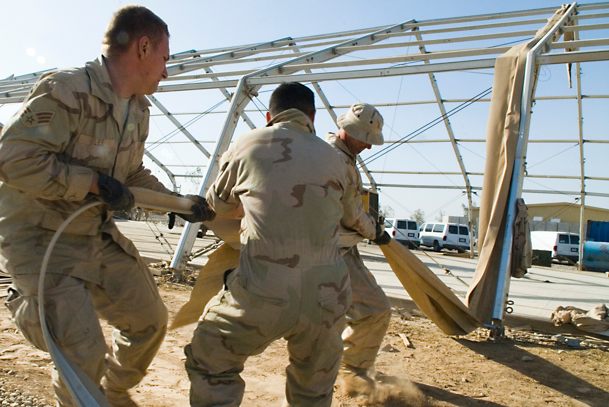 BALAD AIR BASE, Iraq -- Senior Airman Jacob Lee along with fellow 332nd Expeditionary Civil Engineer Squadron mobile team members, pull the remaining canvas from the frame of a Basic Expeditionary Airfield Resources temporary shelter here, Dec. 3. The shelter was disassembled and replaced by a new storage shelter. The Airmen are deployed from Holloman Air Force Base, N.M. (U.S. Air Force photo/Staff Sgt. Joshua J. Garcia) 