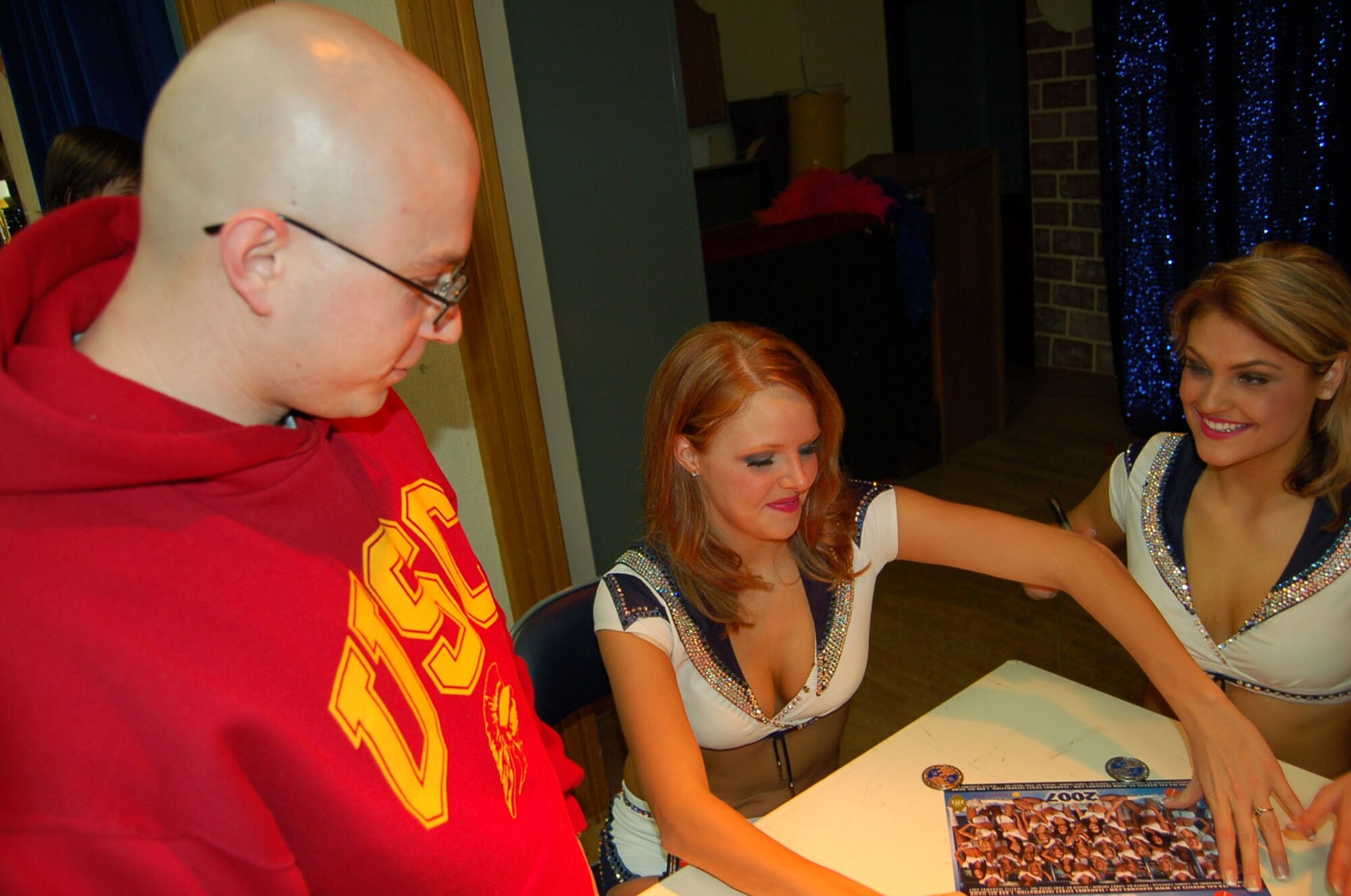 SPANGDAHLEM AIR BASE, Germany -- Senior Airman Martin Schneider, 606th Air Control Squadron, receives autographs from Seattle Seahawks Cheerleaders Tessa and Katie during the Sea Gals’ European Armed Forces Entertainment tour Dec.1, 2007. (U.S. Air Force photo/Capt. Kevin Coffman)
