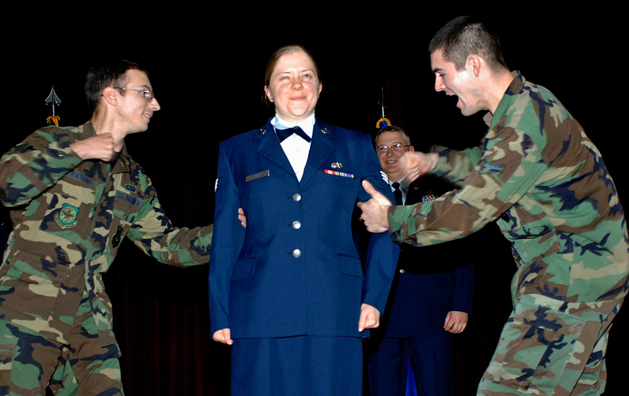 FAIRCHILD AIR FORCE BASE, Wash. – Senior Airman Chad Watkins, 92nd Air Refueling wing public affairs, and Airman 1st Class T.J. Cornell, 92nd Logistics Readiness Squadron, participate in the tradition of “pinning on” by securing stripes to the jacket of Airman 1st Class Jocelyn Ford, 92nd Air Refueling wing public affairs, at the promotion ceremony Nov 30. (U.S. Air Force photo/Staff Sgt. JT May III)