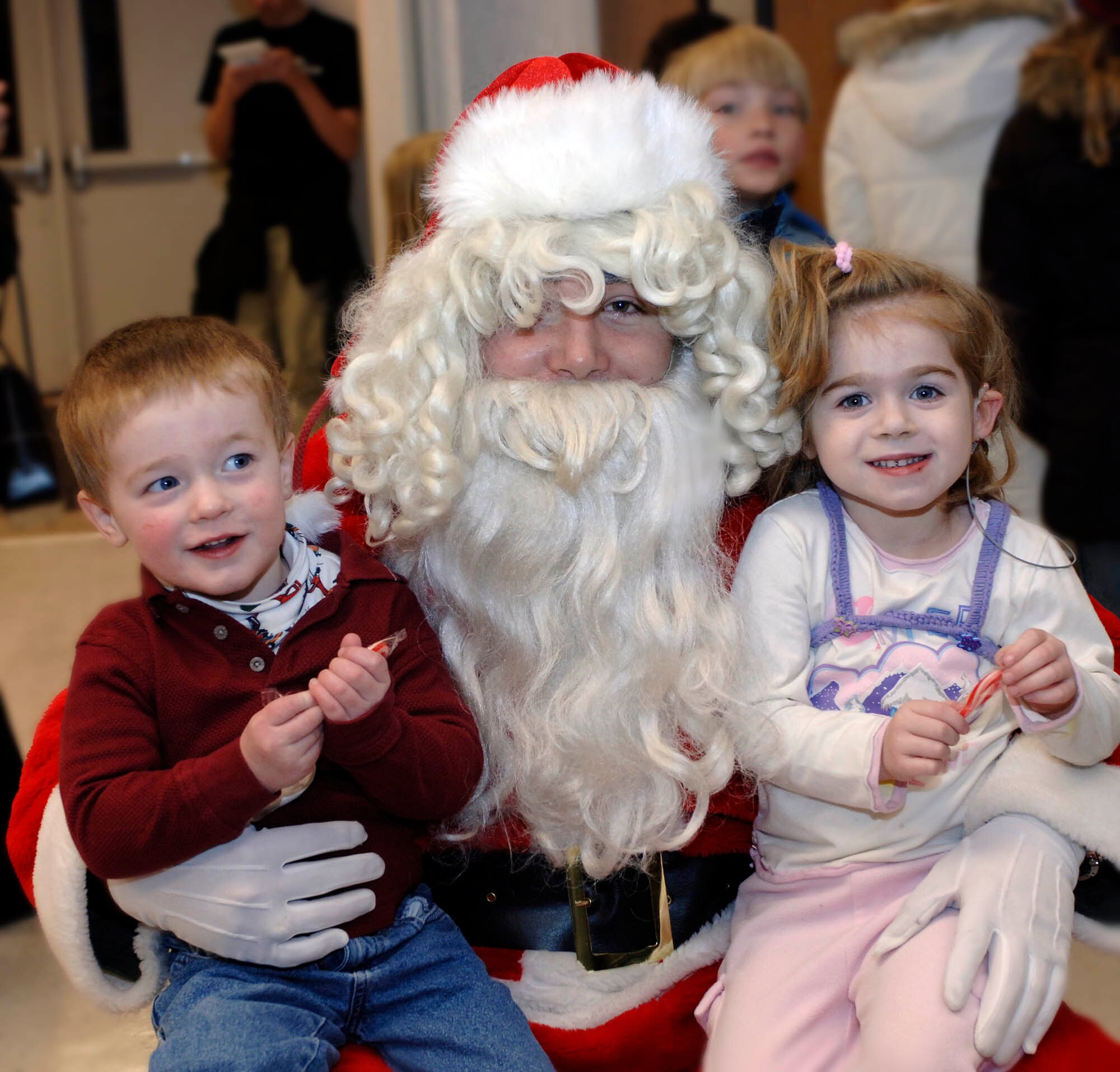 FAIRCHILD AIR FORCE BASE, Wash. – Gavin and Clarice Rhatigan, son and daughter of Lt. Col. Patrick Rhatigan, 92nd Air Refueling Wing chief of wing safety, pose with Santa Claus after the Annual Christmas Tree lighting on Nov. 29. Kids were able to talk to Santa Claus immediately following the lighting. (U.S. Air Force photo / Staff Sgt. JT May III)