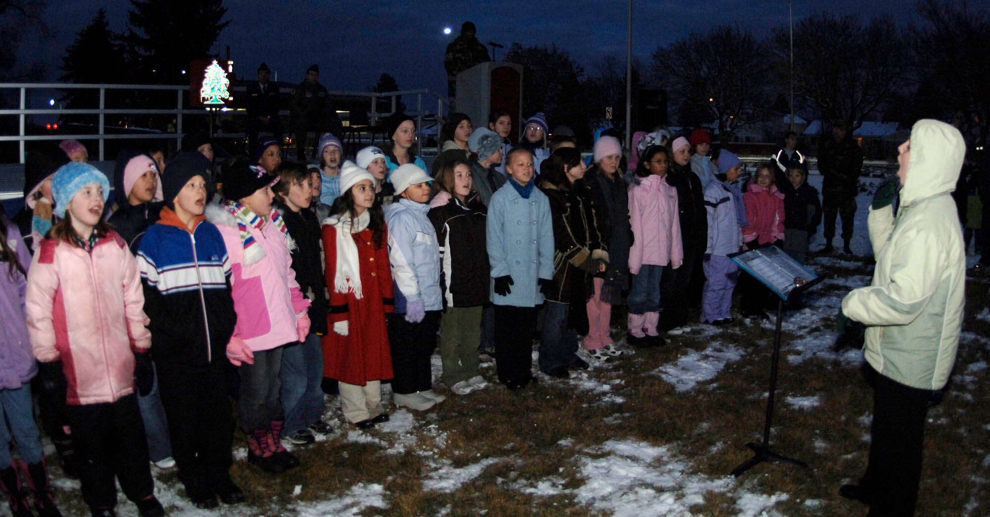 FAIRCHILD AIR FORCE BASE, Wash. – Rachael Dunn, Michael Anderson Elementary School Choir director, leads the Michael Anderson Choraleers in holiday carols during the Annual Christmas Tree lighting Nov. 29. The choir sang a melodic mix of age-old holiday classics, providing a little warmth despite the frigid temperature. (U.S. Air Force photo / Staff Sgt. JT May III)