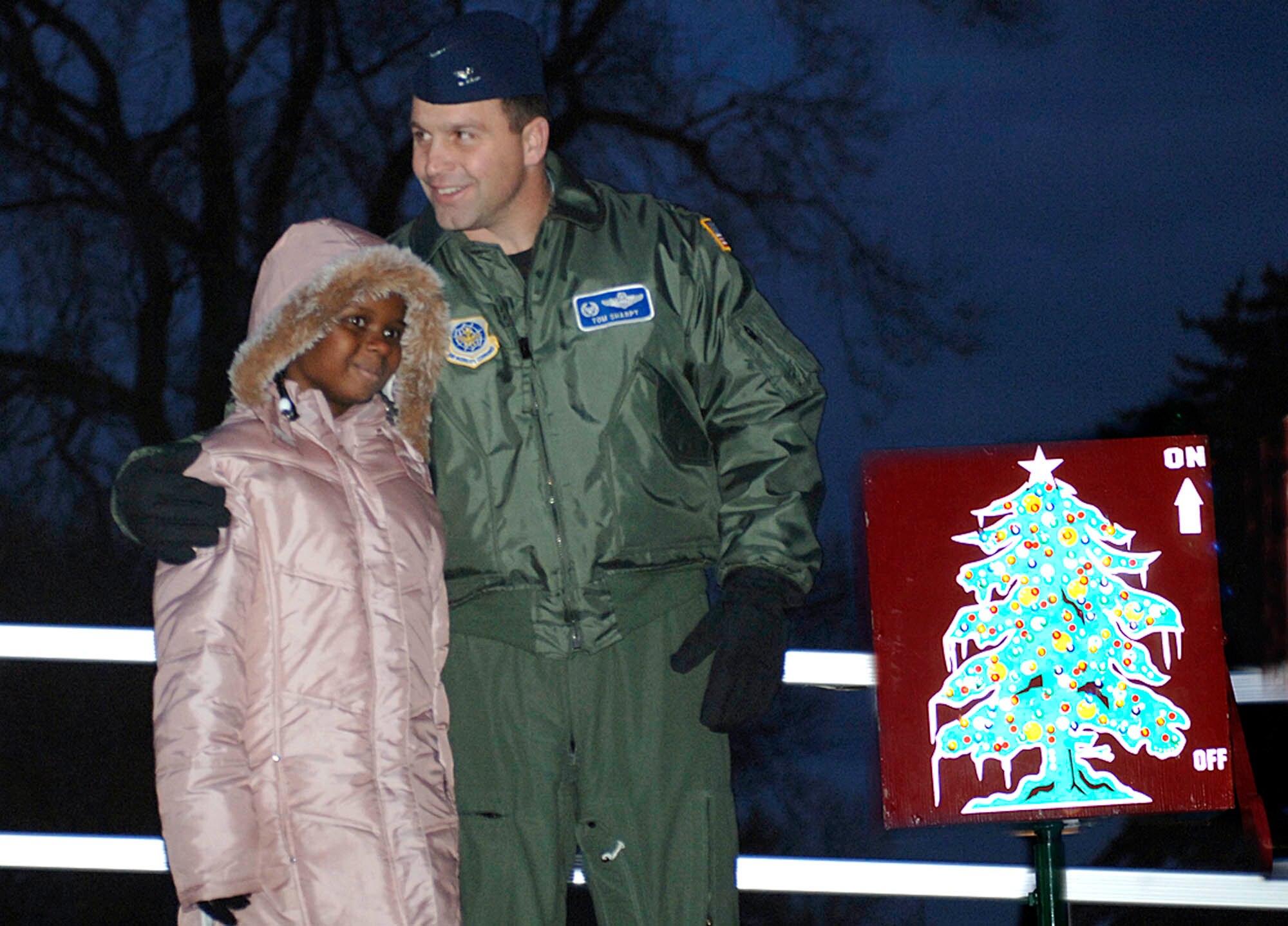 FAIRCHILD AIR FORCE BASE, Wash. – Col. Thomas Sharpy, 92nd Air Refueling Wing commander, and Tija Burns, 7, daughter of Senior Master Sgt. Alisa Burns, 92nd Comptroller Squadron, prepare to “hit the switch” at the Annual Christmas Tree lighting Nov. 29. This event symbolizes the beginning of winter holidays for military members and their families across base. (U.S. Air Force photo / Staff Sgt. JT May III)