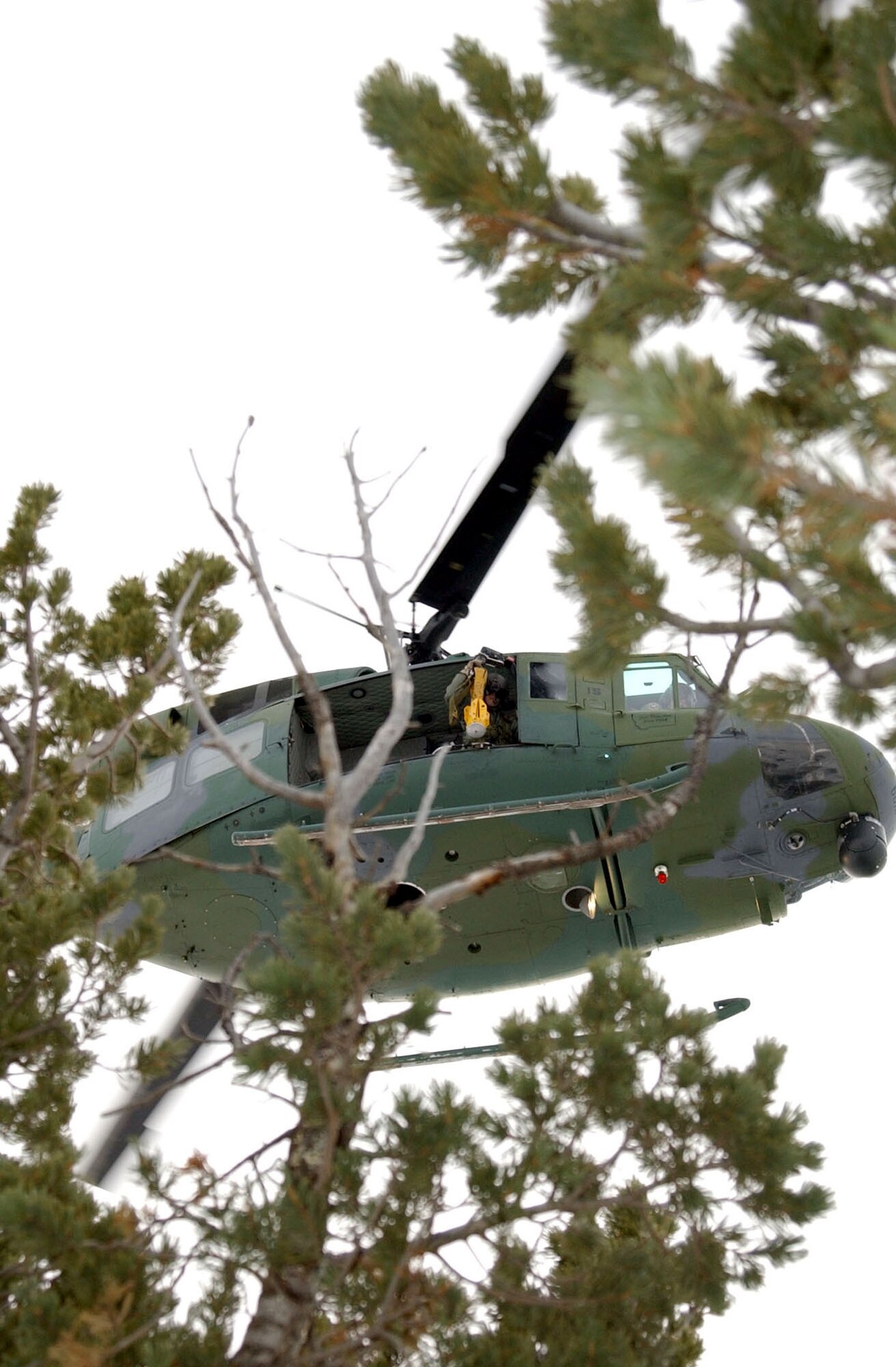 Staff Sgt. Michael Frances, 40th Helicopter Squadron flight engineer, lowers the yellow Forest Penetrator, which is used to insert medical technicians into a wooded area during a search and rescue operation, during a training sortie Nov. 19. (U.S. Air Force photo/Senior Airman Eydie Sakura).         