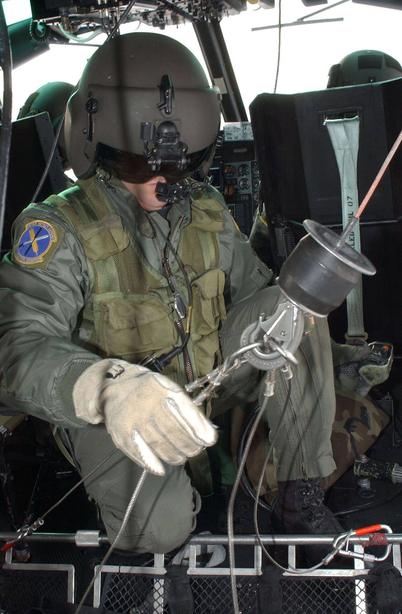 Staff Sgt. Michael Frances, 40th Helicopter Squadron flight engineer, hooks up a stokes litter, a stretcher designed to transport people from the ground to the helicopter while in the air, during a search and rescue training sortie Nov. 19. The stokes litter has multiple attach points, separate hold-down cables and powered extension hoists to help save more lives. (U.S. Air Force photo/Senior Airman Eydie Sakura).