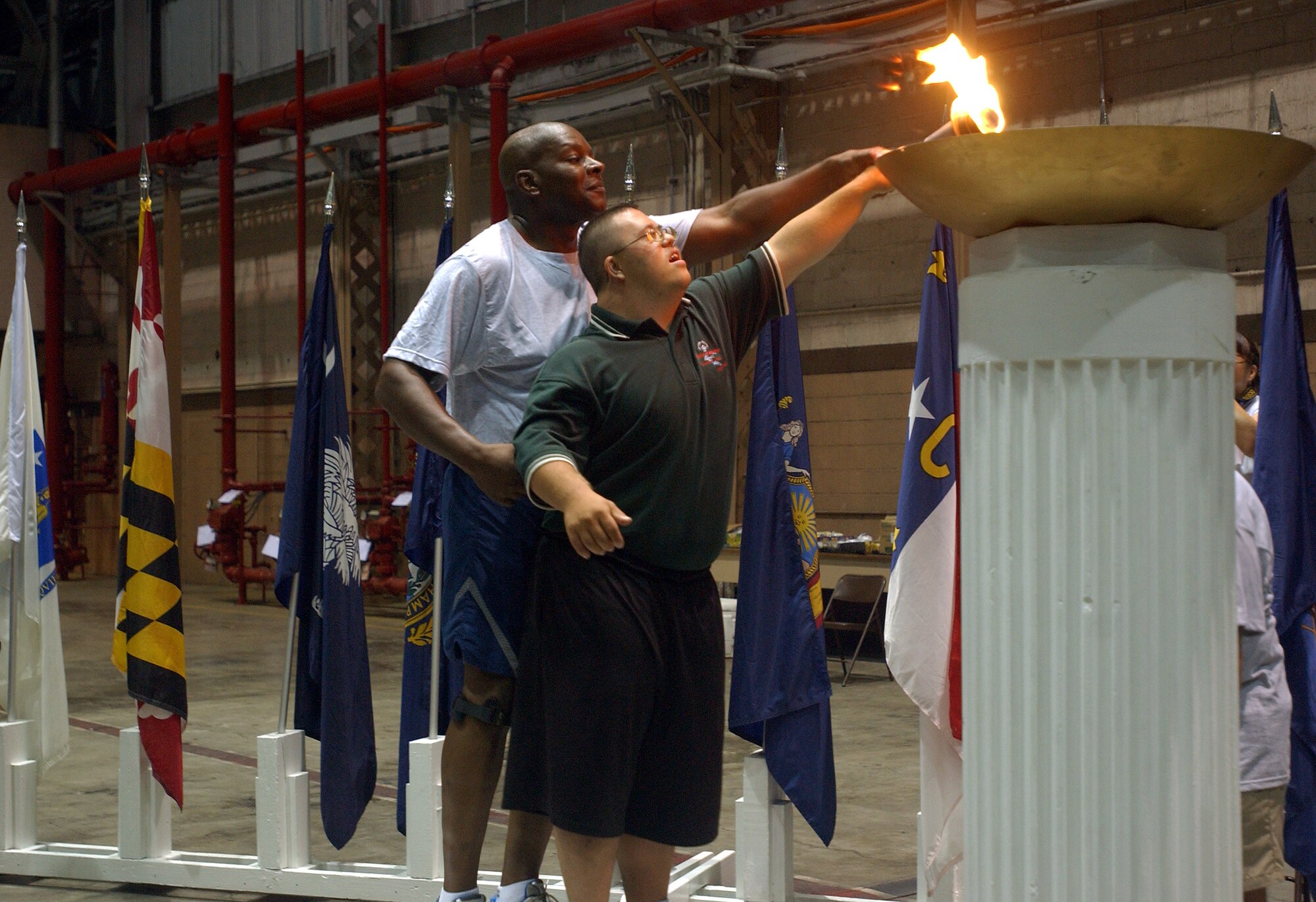 Lt. Col. Charles Moose, 15th Security Forces Squadron commander helps Adrian Cleintuar, Special Olympics athlete light the torch, symbolizing the beginning of the Special Olympics Hawaii Holiday Classic. The Nov. 20 event kicked off a weekend of games at Hickam AFB and Marine Corps Base Hawaii, Kaneohe Bay. Photo by Staff Sgt. Erin Smith.