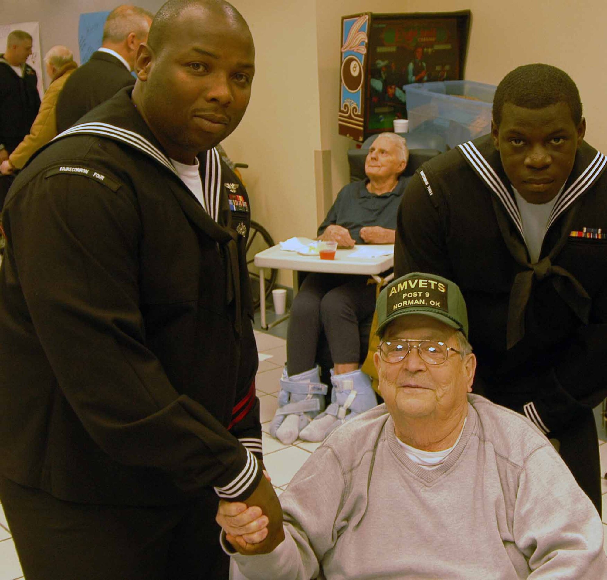 Sailors from Strategic Communications Wing ONE, a part of the Take Charge and Move Out community, stop to pose for a photo with one of the veterans currently receiving treatment at the Norman Veterans Center.  (Photo by Petty Officer 1st Class Jason Keys)