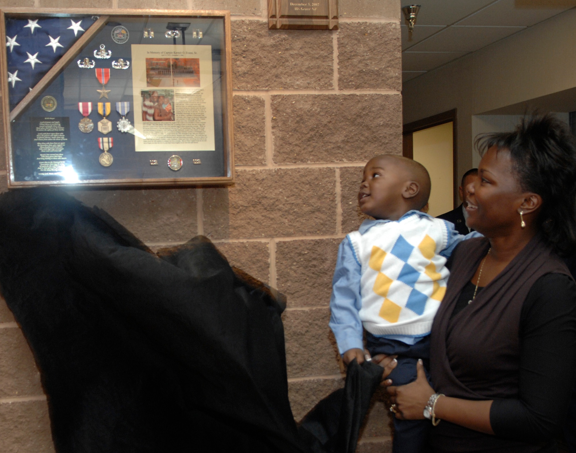 CANNON AIR FORCE BASE, N.M. - Kermit Evans Jr. and his mother, Perneatha, unveil the shadow box dedicated to Capt. Kermit Evans, former flight commander of the 27th Special Operations Civil Engineering Squadron's EOD flight Dec. 3. The memorial dedication took place on the one-year anniversary of Capt. Evans' death in Iraq. (U.S. Air Force photo by Airman 1st Class Erik Cardenas)