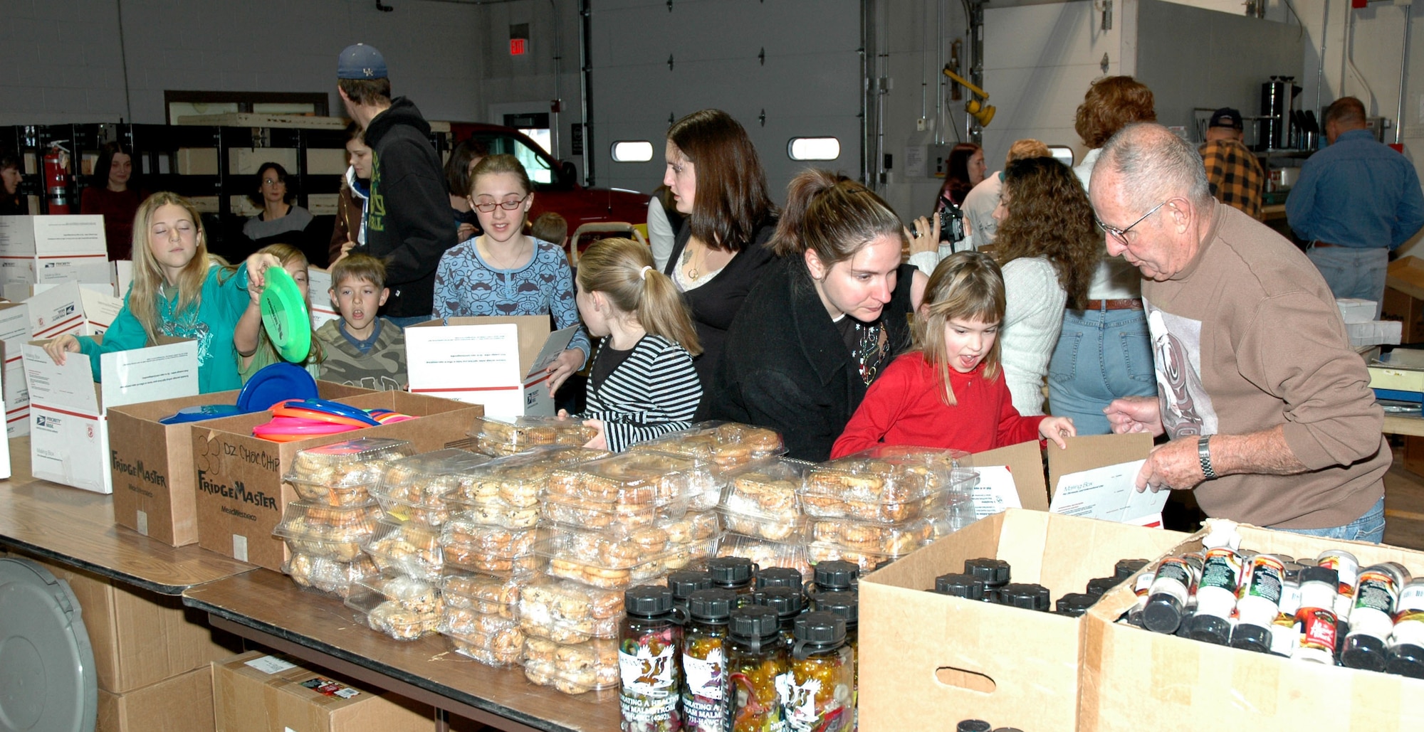 Family members, servicemembers and volunteers from Malmstrom Air Force Base and the Great Falls community add items to care packages at the traffic management office Dec. 1. Roughly 400 packages were sent the same day to deployed servicemembers from Montana. (U.S. Air Force photo/Airman 1st Class Dillon White)