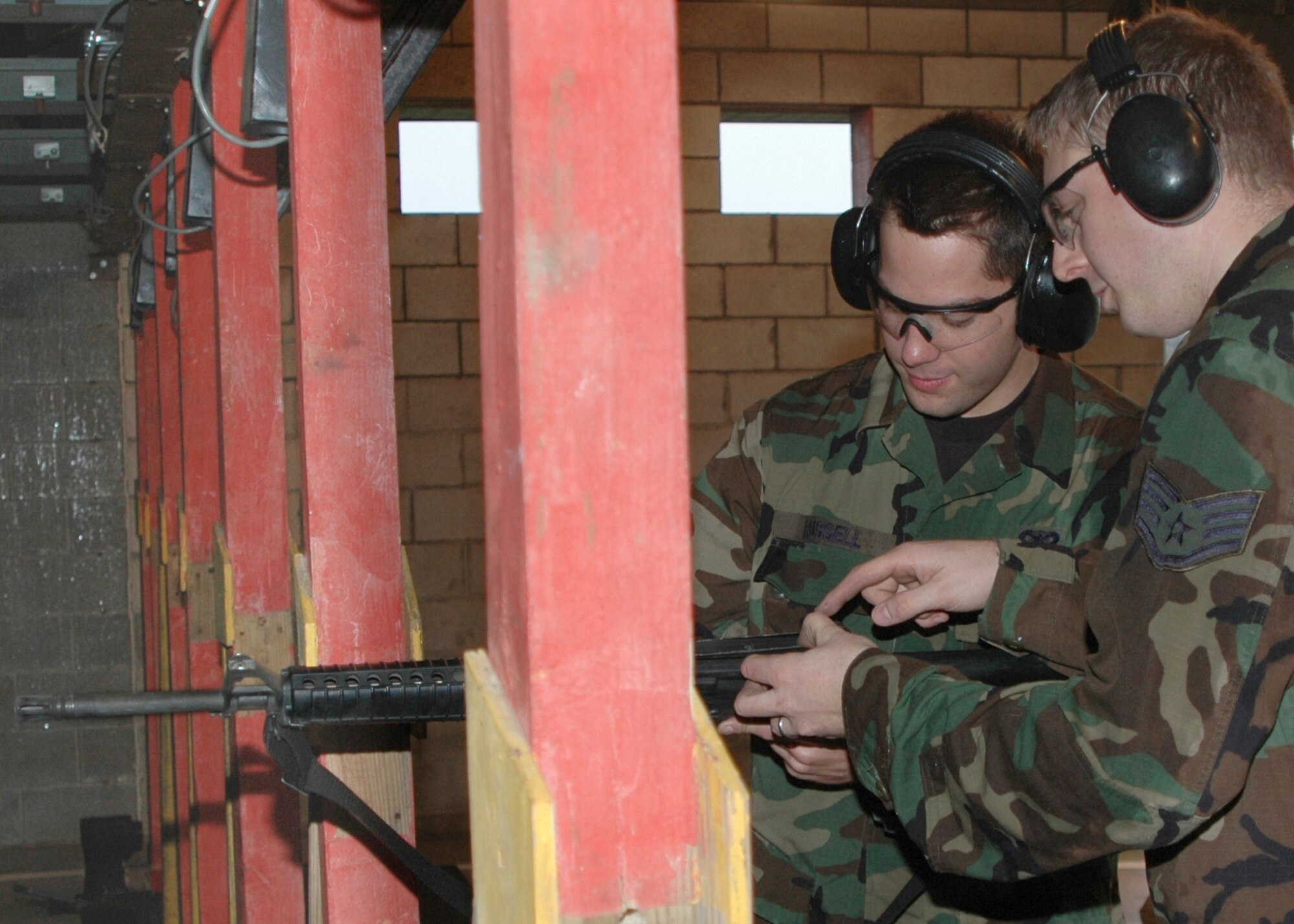 GRISSOM AIR RESERVE BASE, Ind., -- Senior Airman Tony Russell, right, and Staff Sgt. Dustin Lindley, both combat arms instructors with the 434th Security Forces Squadron perform their annual proficiency firing.  Proficiency firing is used to improve the firing skills of the instructor.  Airman Russell fires the weapon while Sergeant Lindley practices his instructor skills by observing the techniques used by the Airman. (Air Force photo / Senior Airman Ben Mota)