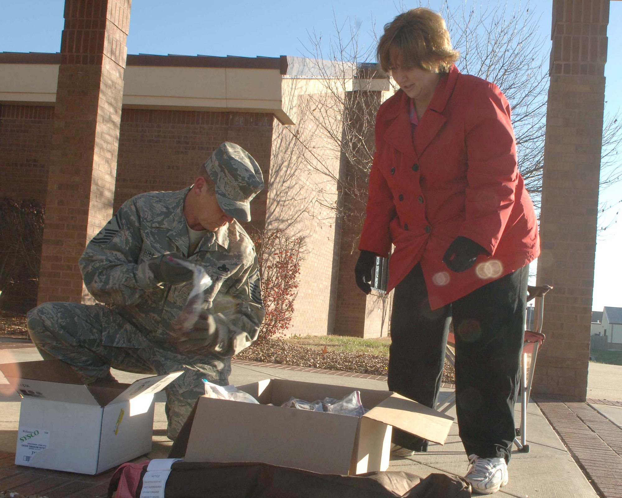Master Sgt. Dean Hill, 509th Maintenance Operation Squadron First Sergeant and Christina Lynch, wife of Major Mark Lynch, 509th Logistics Readiness Squadron, pack cookies collected during the cookie drive at Mission’s End Dec. 4.  The cookie drive was held to collect cookies for the airman who reside on base. (U.S. Air Force photo/Staff Sgt. Felicia R. Haecker) 
