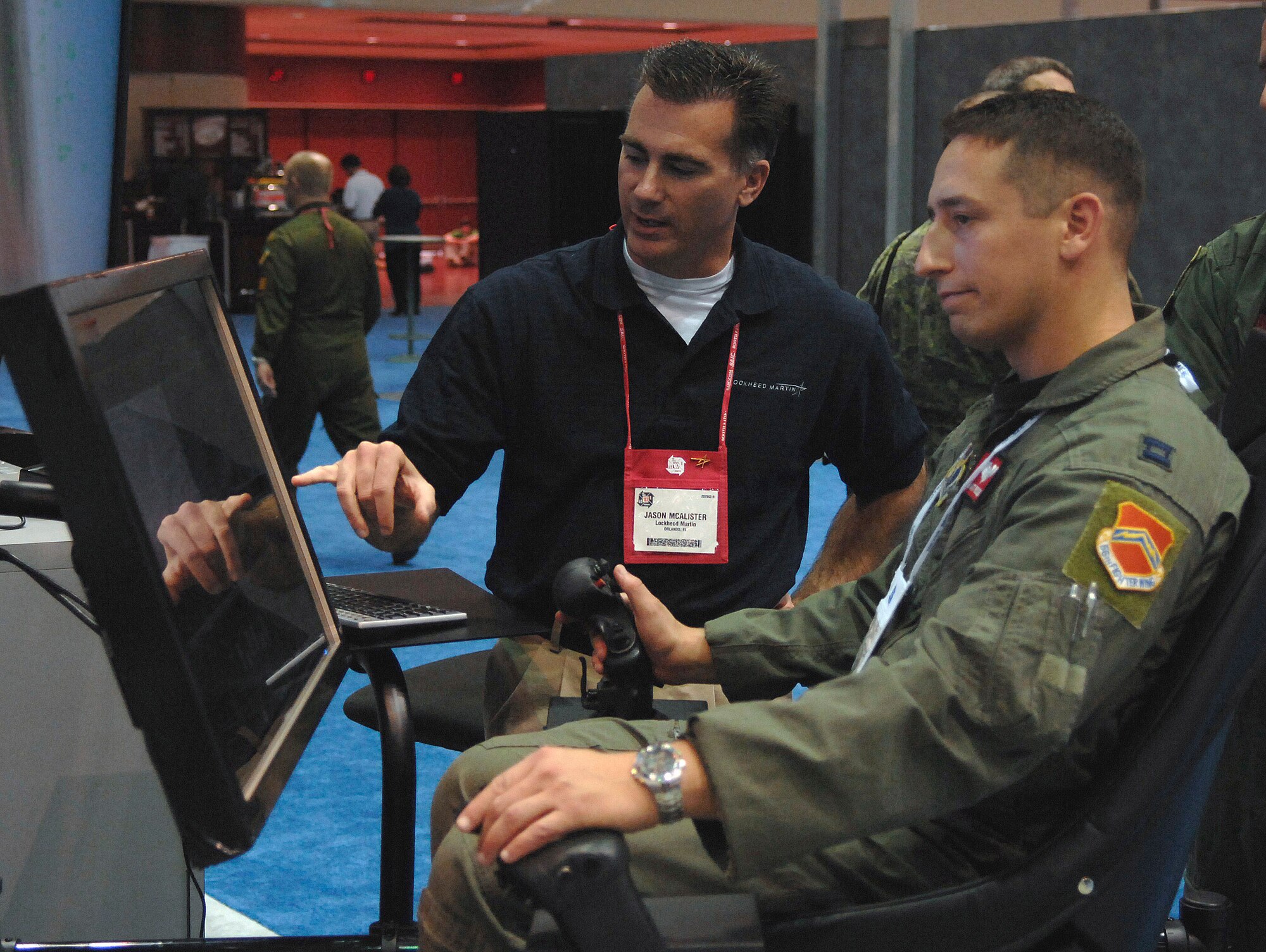 Capt. Matt Poisson (right) tries out some of the newest technology on an F-35 Joint Strike Fighter simulator while Jason McAlister from Lockheed Martin instructs him on the new displays Nov. 30 during the Interservice/Industry Training, Simulation and Education Conference in Orlando, Fla. Captain Poisson is F-16 Fighting Falcon pilot from Luke Air Force Base, Ariz. (U.S. Air Force photo/Tech. Sgt. Larry A. Simmons) 
