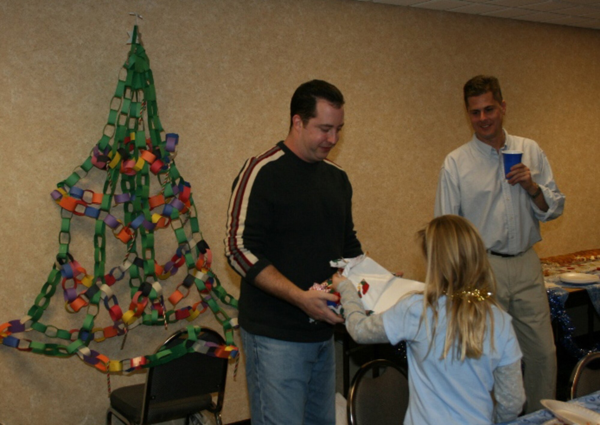 SEYMOUR JOHNSON AIR FORCE BASE, N.C.-- The 916th Communication Squadron celebrated the December unit training assembly with a holiday party for their more than 70 troops. Here Tech Sgt. Michael Burbank gives a gift to Rebecca Fitzmaurice, daughter of Master Sgt. Jennifer Conway, during a Secret Santa game.