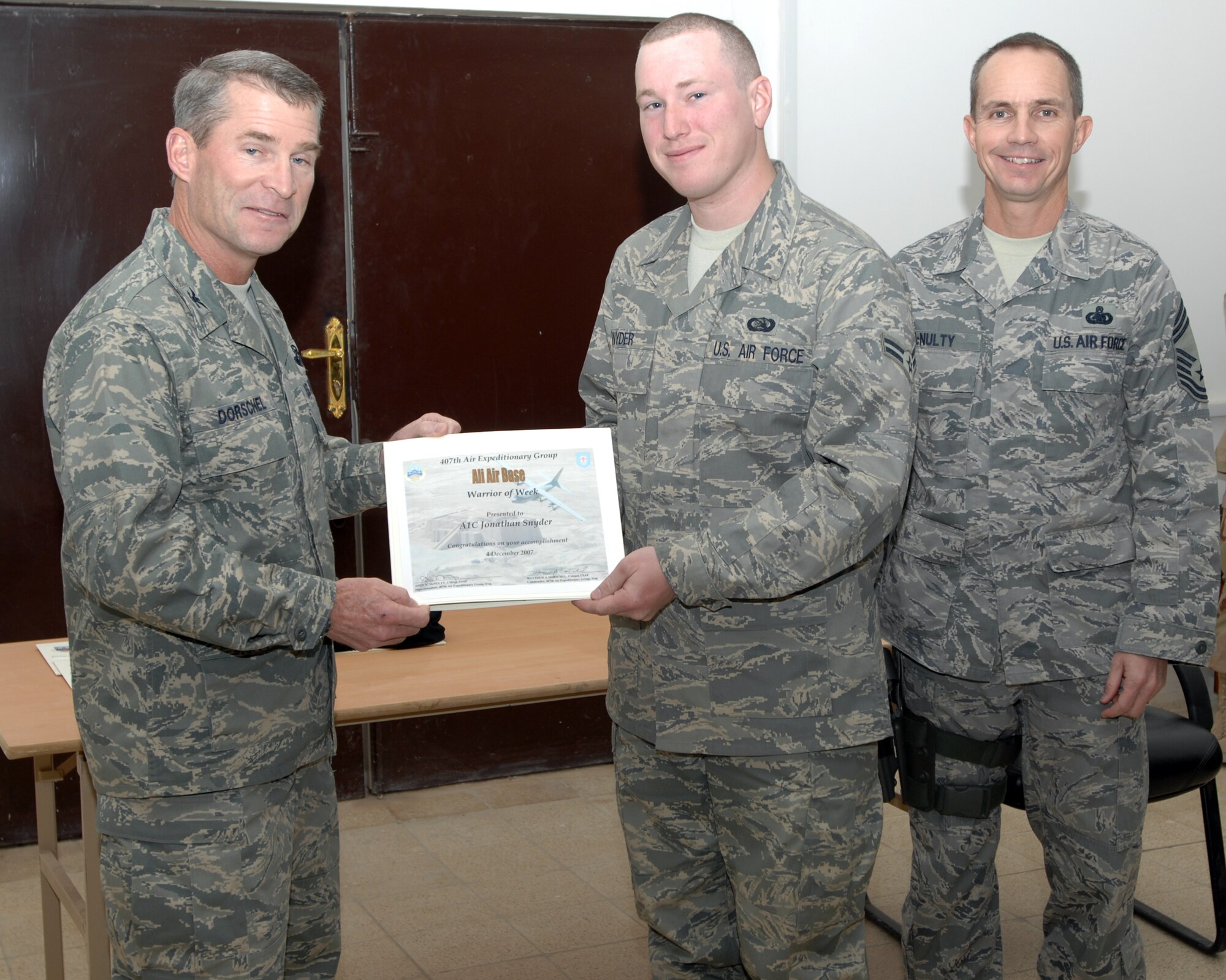 ALI AIR BASE, Iraq -- Colonel Matthew Dorschel presents Airman First Class Jonathan Snyder a certificate for being selected as the Warrior of the Week ending Dec 4. Airman Snyder is a Photographer with the 407th Air Expeditionary Group, Public Affairs office and is deployed from Eielson Air Force Base, Alaska. The WOW program, managed by chief enlisted manager and run by the squadrons' first sergeants, is intended to highlight outstanding behind-the-scenes performers. The winner is presented the WOW award by the 407th Air Expeditionary Group commander. (U.S. Air Force photo/Master Sgt. Rob Wieland)