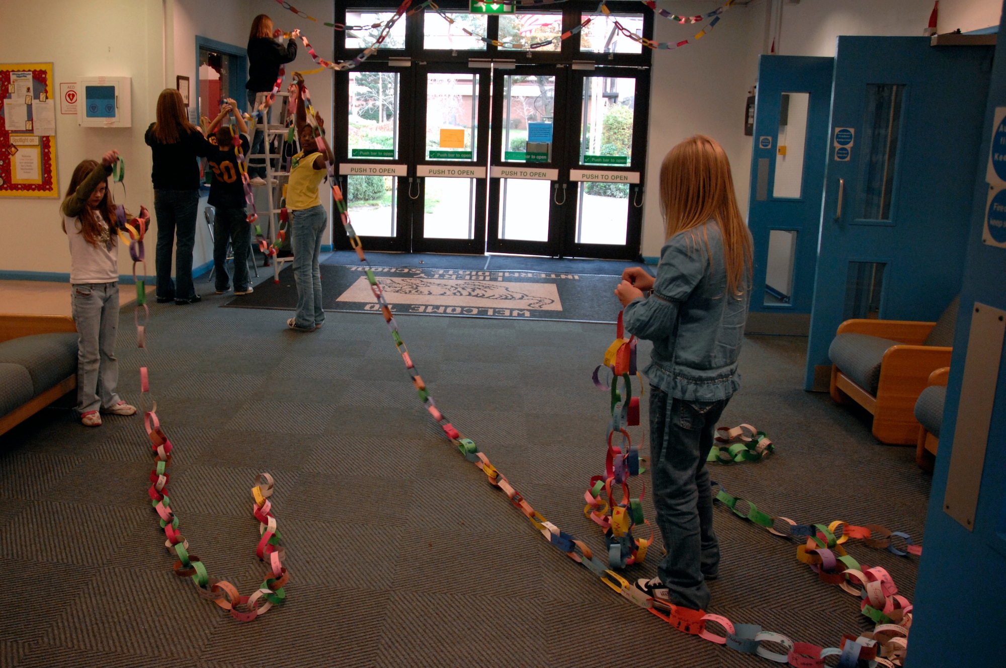 Students and teachers hang chained construction paper together Nov. 30 at Lakenheath Intermediate School, RAF Lakenheath, England. The project is called, "Chain of Peace." Students used pre-cut pieces of construction and wrote encouraging or heartfelt wishes to deployed Airmen and Soldiers. (U.S. Air Force photo by Airman Perry M. Aston) 