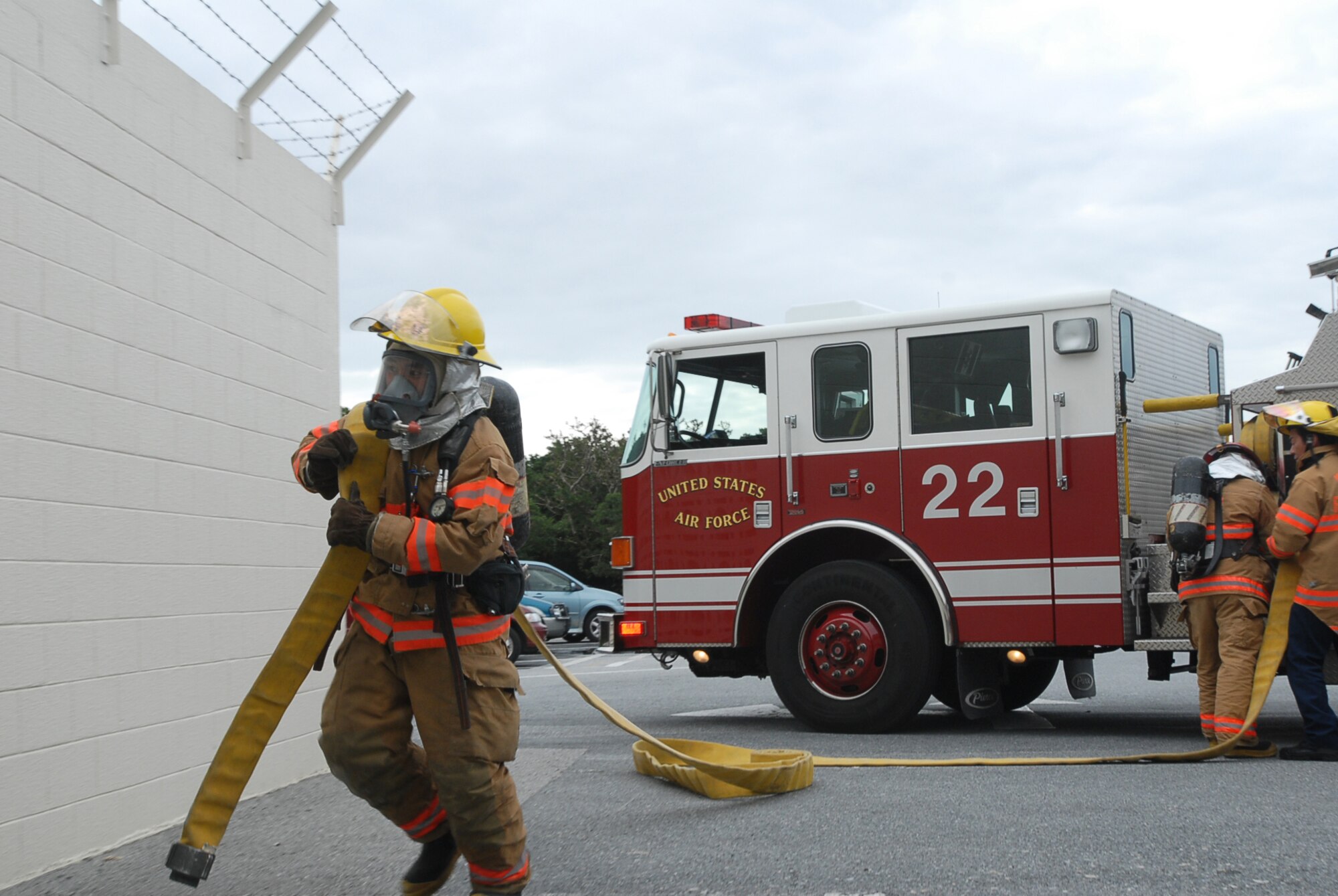 A base firefighter carries a fire hose to put out a simulated fire during a Local Operational Readiness Exercise Beverly High 08-02 scenario at Kadena Air Base, Japan, Dec. 4, 2007. This scenario tested the firefighters ability to respond to a fire while working with other agencies. (U.S. Air Force /Senior Airman Darnell T. Cannady)  
