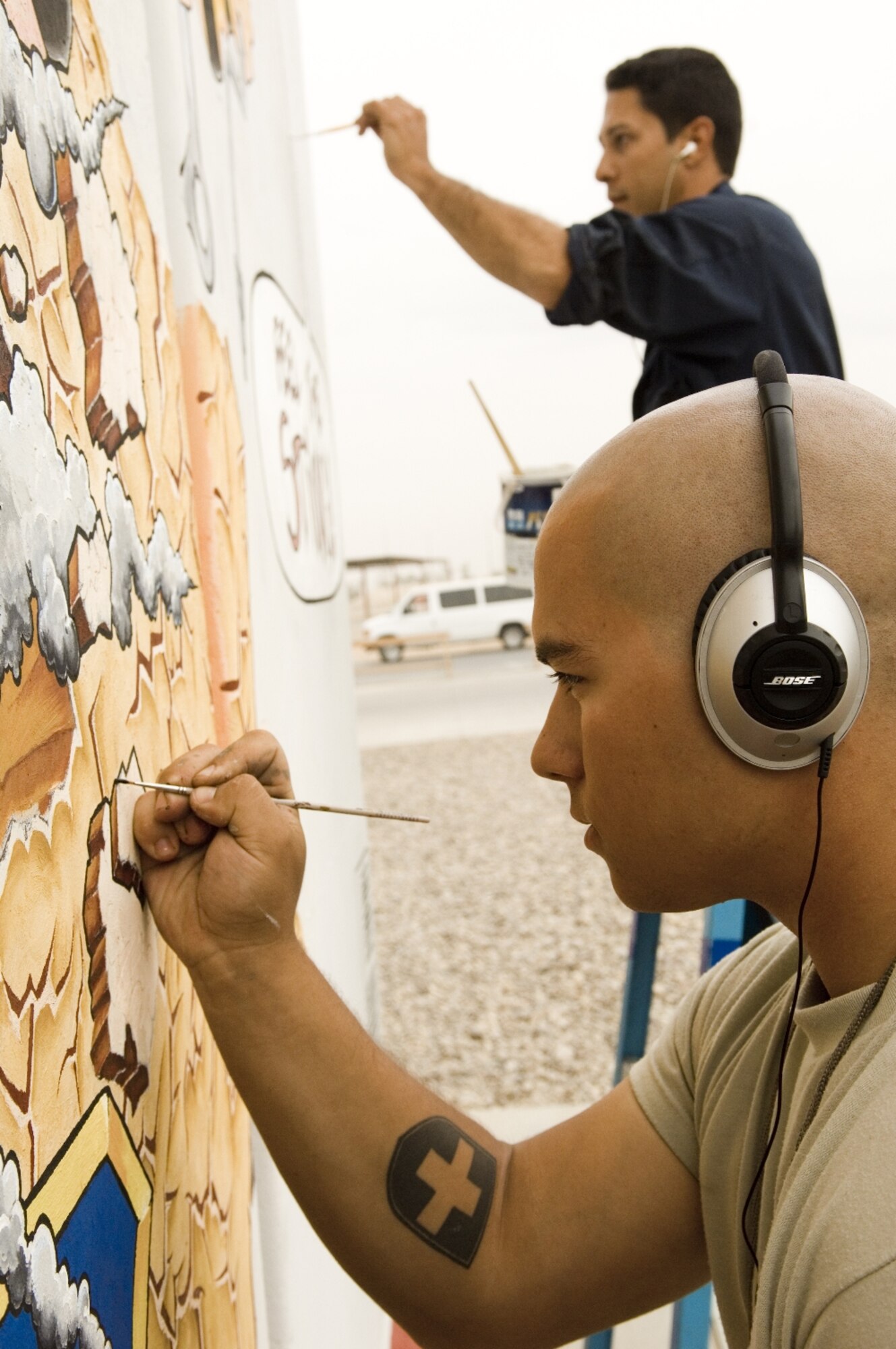 BALAD AIR BASE, Iraq -- Airman 1st Class Andre Cotan, front, and Airman 1st Class Francisco Coraliz, both from the 332nd Expeditionary Aircraft Maintenance Squadron, add details on a mural they are painting to commemorate their units time in Iraq. Following approved guidelines, deployed members are encouraged to paint to build unit morale. Airmen Cotan and Coraliz are deployed from Spangdahlem Air Force Base, Germany. (U.S. Air Force photo/Staff Sgt. Travis Edwards)