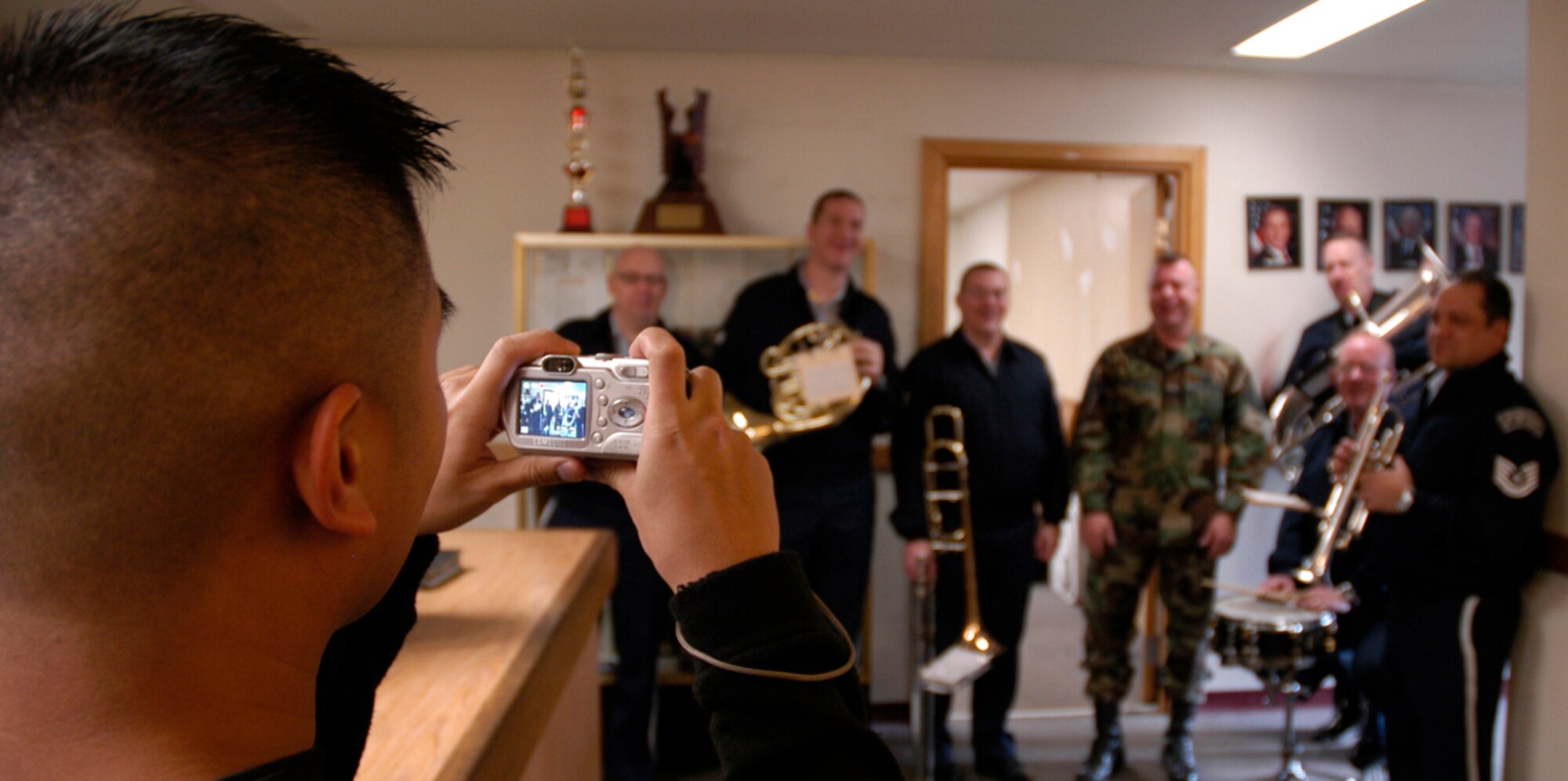KUNSAN AIR BASE, South Korea -- Staff Sgt. Joseph Joson, 8th Aircraft Maintenance Squadron takes a photo of a coworker with the Air Force Band of the Pacific after a caroling stop during the groups visit to the unit Dec. 4. The Elmendorf Air Force Base, Alaska based band is here for a week spreading holiday cheer across the base and in the local Gunsan City area. (U.S. Air Force Photo/Master Sgt. Sean P. Houlihan)