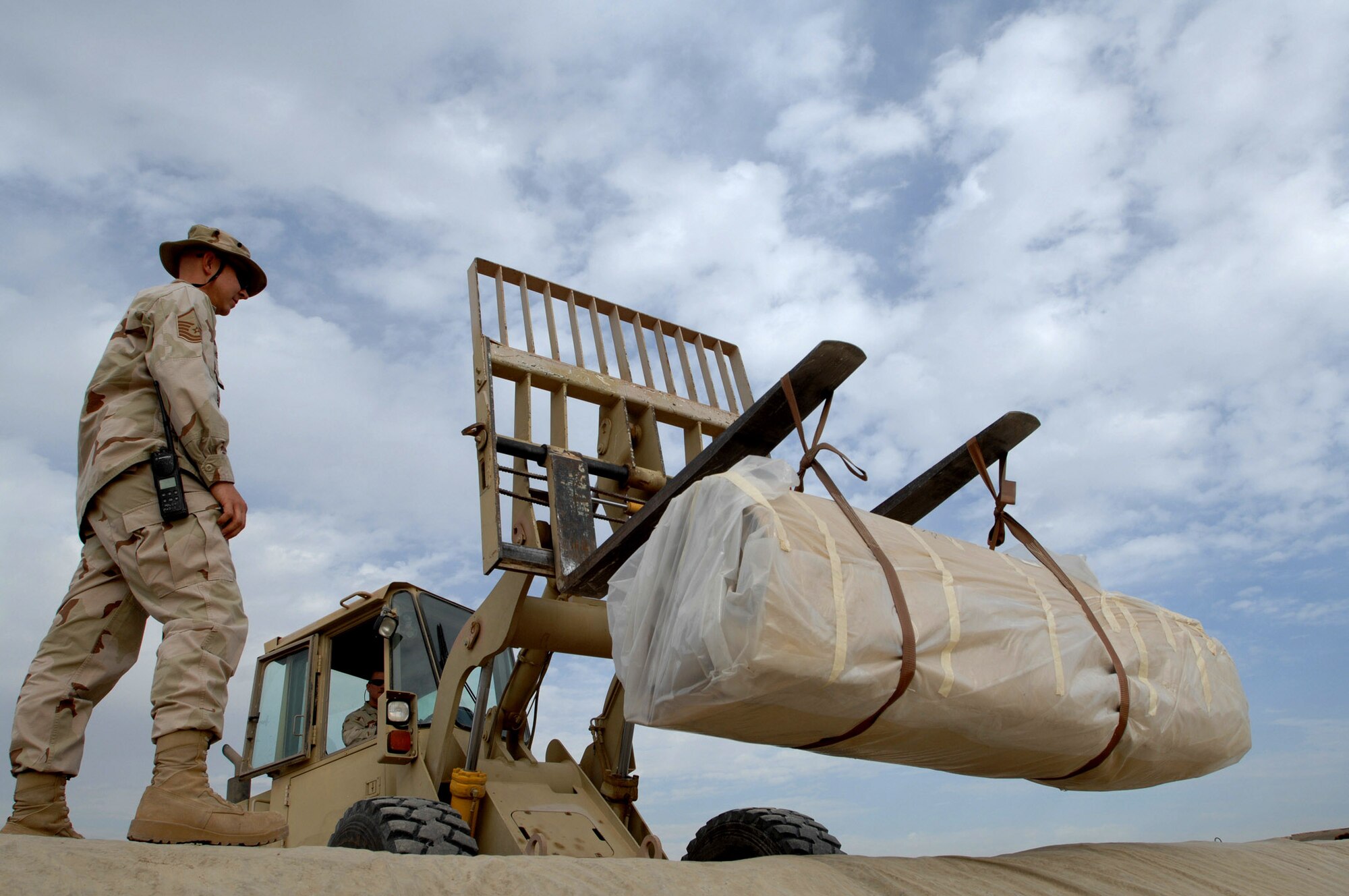 Master Sgt. Wade Headlee observes as a new 900-pound fuel bladder is lowered into a hole Dec. 3 at Ali Base, Iraq. Airmen from the 407th Expeditionary Logistics Readiness Squadron fuels shop periodically replace fuel bladders to prevent ruptures.  The new bladder can hold up to 50,000 gallons of fuel. Sergeant Headlee is deployed from Kadena Air Base, Japan. (U.S. Air Force photo/Airman 1st Class Jonathan Snyder) 