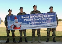 During a press conference at Lackland Air Force Base, Texas, on Dec. 4, Airmen from the 37th Security Forces Squadron hold the English version of TxDOT's whimsical drunken driving prevention campaign poster. The conference announced the start of the Texas Department of Transportation's annual four-week holiday campaign. All the campaign material, to include television commercials,  billboards, adverstisements at gas stations and cardboard coasters, are printed in English and Spanish. The Airmen, from left, are Airman 1st Class Randolph Rivera, Airman Michael Gans, Airman 1st Class Kurt Cornwell and Airman 1st Class Austin Best. (USAF photo by Alan Boedeker)                               