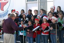 The Heritage Middle School all-girl choir sings "Here Comes Santa Claus" as Brig. Gen. Darrell Jones' newest Wingman and purveyor of wished-for toys floats to the ground at Lackland Air Force Base, Texas, on Dec. 4, 2007. The choir was on hand to support the opening of TxDOT's annual four-week drunken driving prevention campaign. This is the 10th year of the Texas Department of Transportation's holiday public education campaign. General Jones is a former commander of the 37th Training Wing.  (USAF photo by Alan Boedeker)