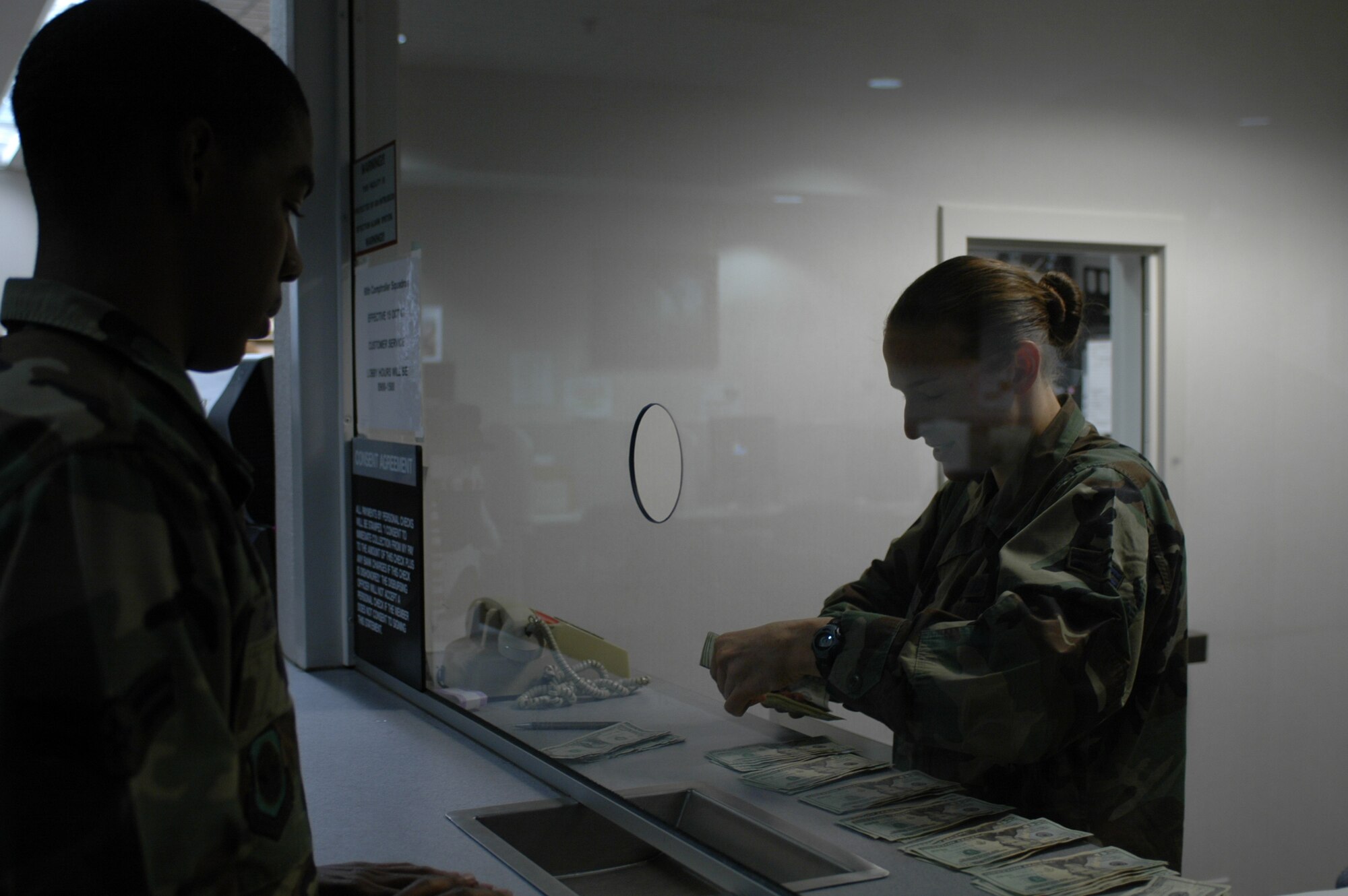 Airman 1st Class Melina Levesque counts out pay for Airman 1st Class Justin Cureton, 60th Aircraft Maintenance Squadron. Travis’ 60th Comptroller Squadron is in the midst of “transformation,” a process which will thin the size of its staff and relocate jobs to Ellsworth Air Force Base in South Dakota. (U.S Air Force photo/Nick DeCicco)