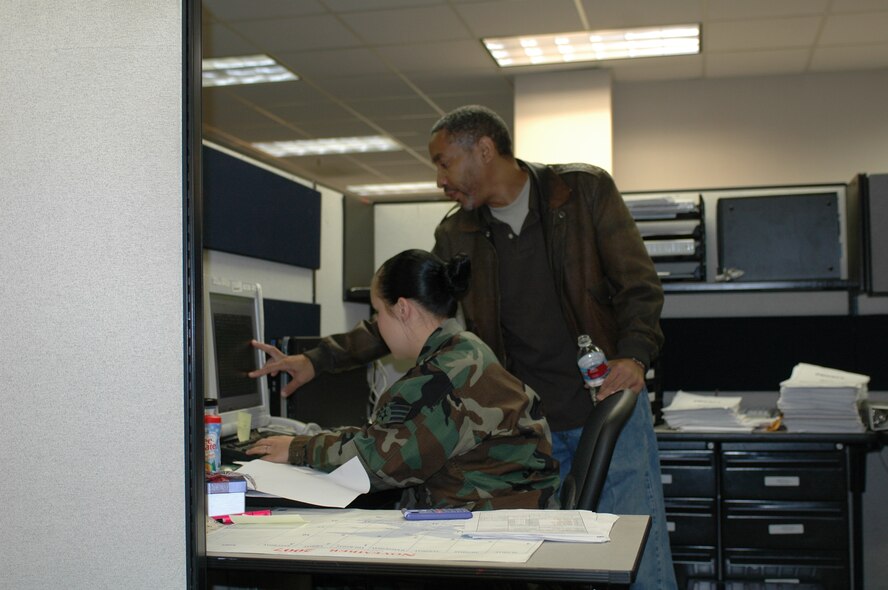 Darryl Thomas instructs Senior Airman Pamela Coats on an aspect of military pay processing. Civilians play a key role in the squadron’s ability to handle a heavy workload, as well as providing institutional knowledge about what has and has not worked in the past. (U.S Air Force photo/Nick DeCicco)