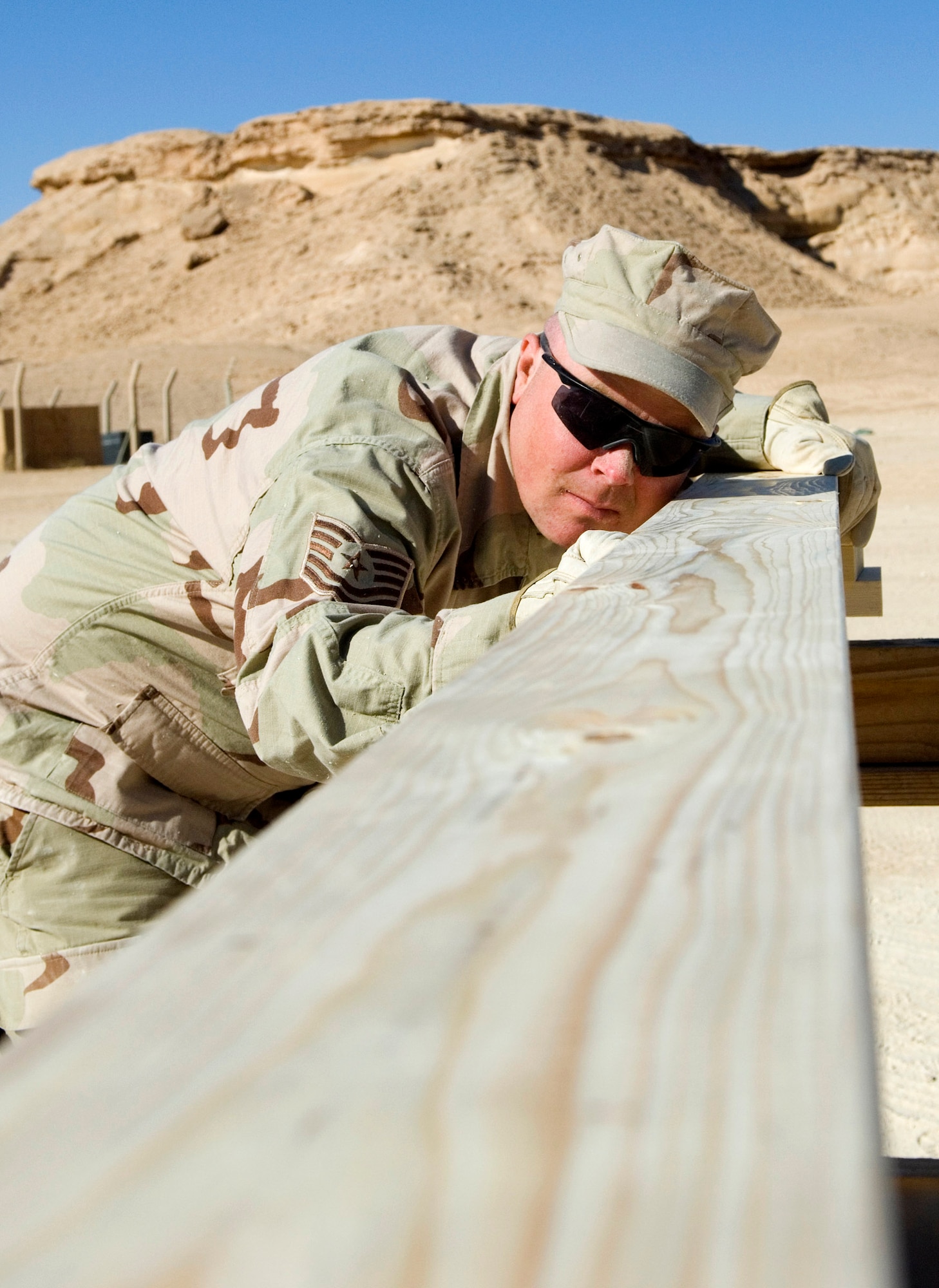 Tech. Sgt. Chris Collins lines up a 2-by-6 board to saw it to size Nov. 24 at Al Asad Air Base, Iraq. The wood he is cutting will be used to frame a bench inside the small-arms classroom his team built for the Marines. REDHORSE Airmen are performing "in-lieu-of" taskings for the 20th Army Engineer Brigade. Sergeant Collins, a 557th Expeditionary REDHORSE utilities technician, is deployed from Minot Air Force Base, N.D. (U.S. Air Force photo/Staff Sgt. Travis Edwards)