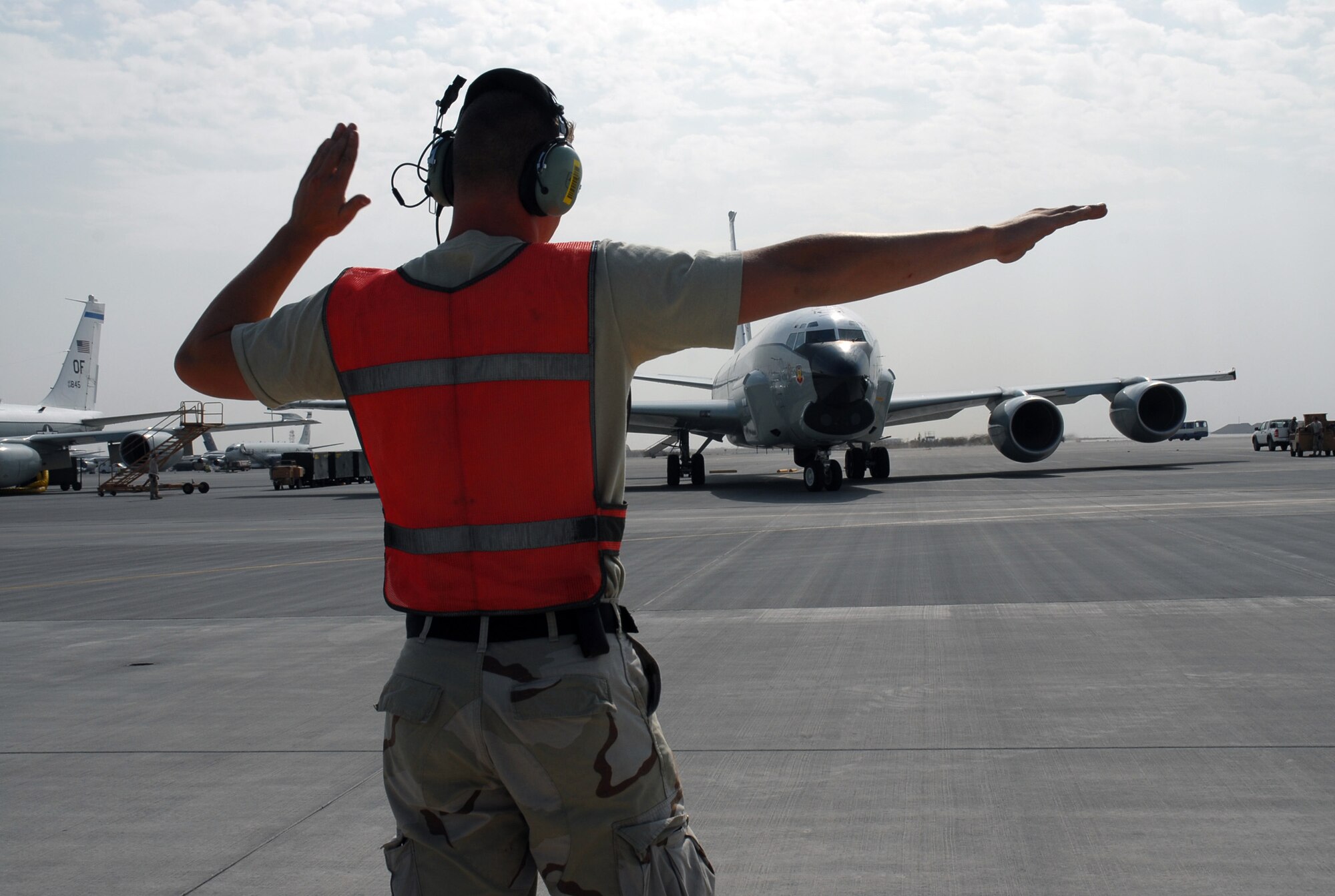 SOUTHWEST ASIA - Senior Airman Mark Butterfield, 379th Expeditionary Aircraft Maintenance Squadron marshalls a RC-135 into position to taxi to the runway for take off Dec. 4 at a base in Southwest Asia. Airman Butterfield is deployed from Offutt AFB,  Neb. and his hometown is Syracuse, N. Y. (U. S. Air Force photo/Staff Sgt. Douglas Olsen)