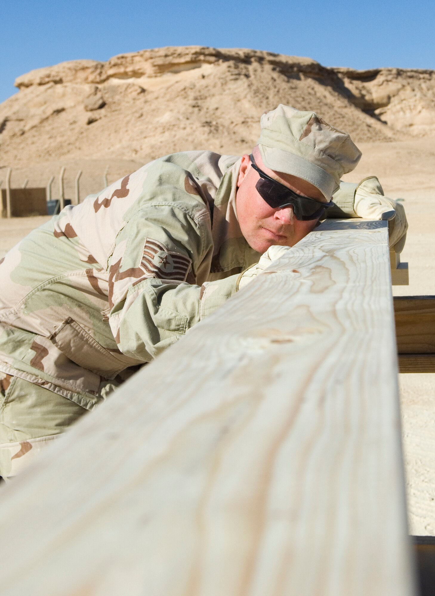 AL ASAD AIR BASE, Iraq -- Tech. Sgt. Chris Collins, a 557th Expeditionary REDHORSE utilities technician, lines up a 2-by-6 board to saw it to size here. The wood he is cutting will be used to frame a bench inside the small-arms classroom his team built for the Marines. REDHORSE Airmen are performing “in-lieu-of” taskings for the 20th Army Engineer Brigade. Sergeant Collins is deployed from Minot Air Force Base, N.D. (U.S. Air Force photo/Staff Sgt. Travis Edwards)