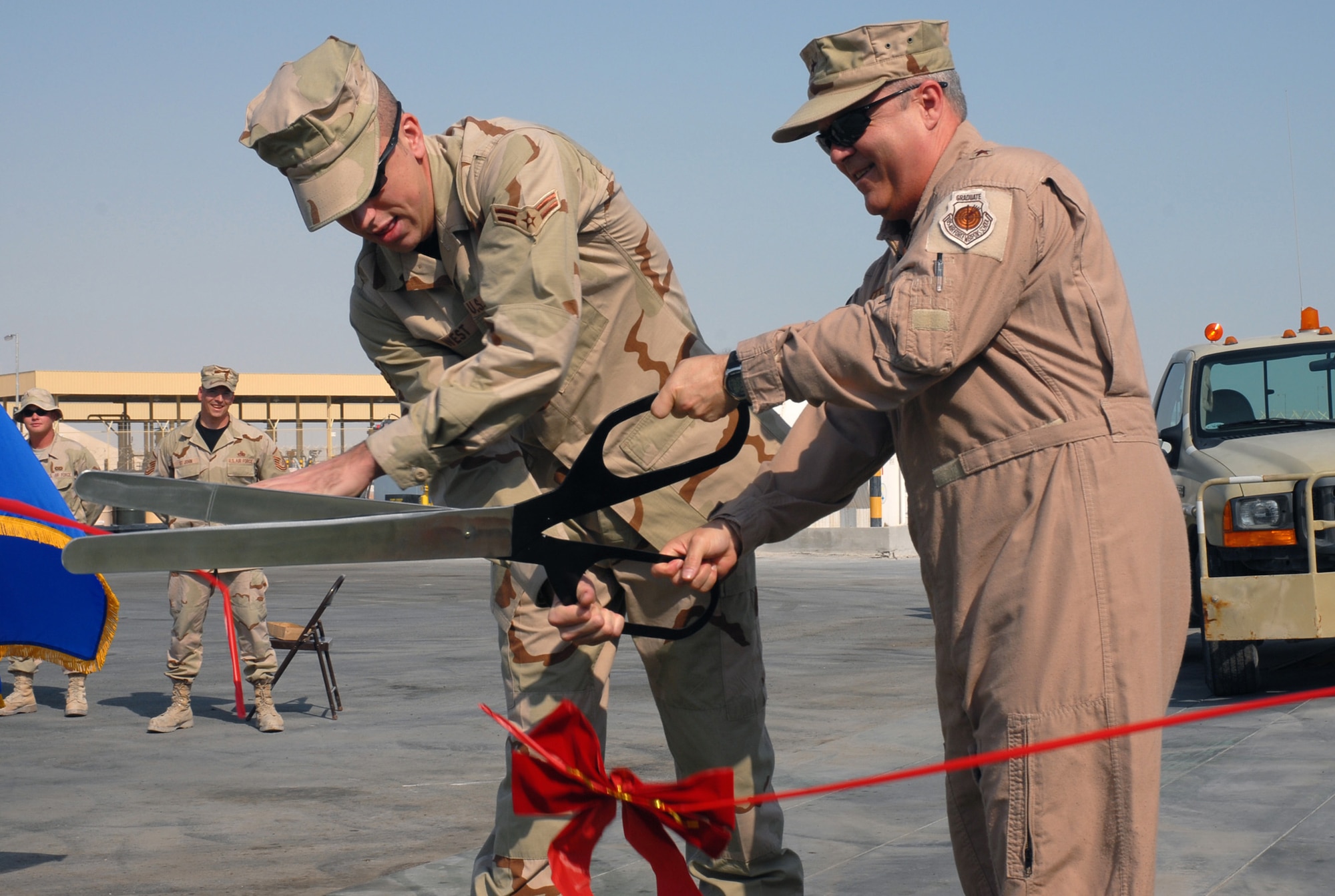 SOUTHWEST ASIA - Airman First Class Michael West, 379th Expeditionary Maintenance Squadron, and Brig. Gen. Charlie Lyon, 379th Air Expeditionary Wing commander,  cut the ribbon to open a newly installed vehicle wash rack at a Southwest Asia air base Dec. 3. The functional wash rack marks a milestone in the Air Ground Equipment shop's development project at this desert base. (U. S. Air Force photo/Staff Sgt. Douglas Olsen)