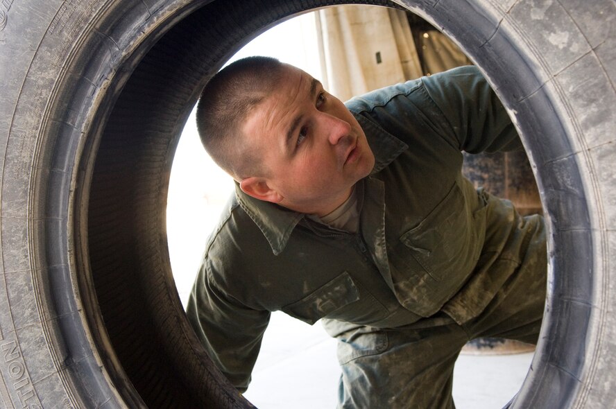 AL ASAD AIR BASE, Iraq -- Senior Airman Matthew Byrd, a 557th Expeditionary REDHORSE vehicle maintenance technician, inspects a punctured tire. Airman Bird patched the tire to use it as a spare. Airman Byrd is deployed from Barksdale Air Force Base, La. (U.S. Air Force photo/Staff Sgt. Travis Edwards)