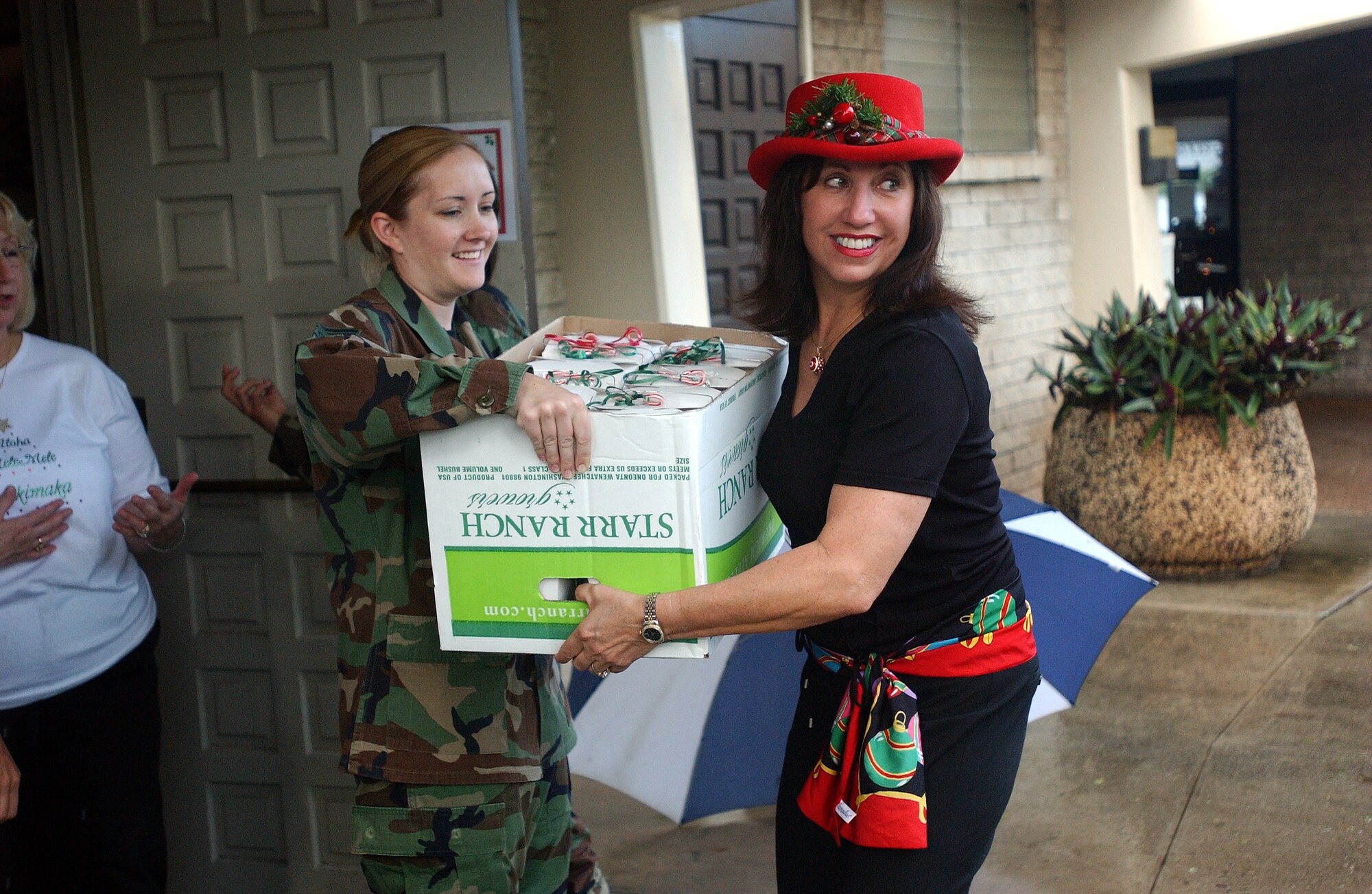 Staff Sgt. Shannon Stokes, 15th Medical Group, hands a box of packaged cookies to Mrs. Irene Torres for delivery to the dormatories. Cookies are being delivered to various units on Hickam AFB, as well as deployed Airmen and those who live in the dormitories. Photo by Staff Sgt. Erin Smith