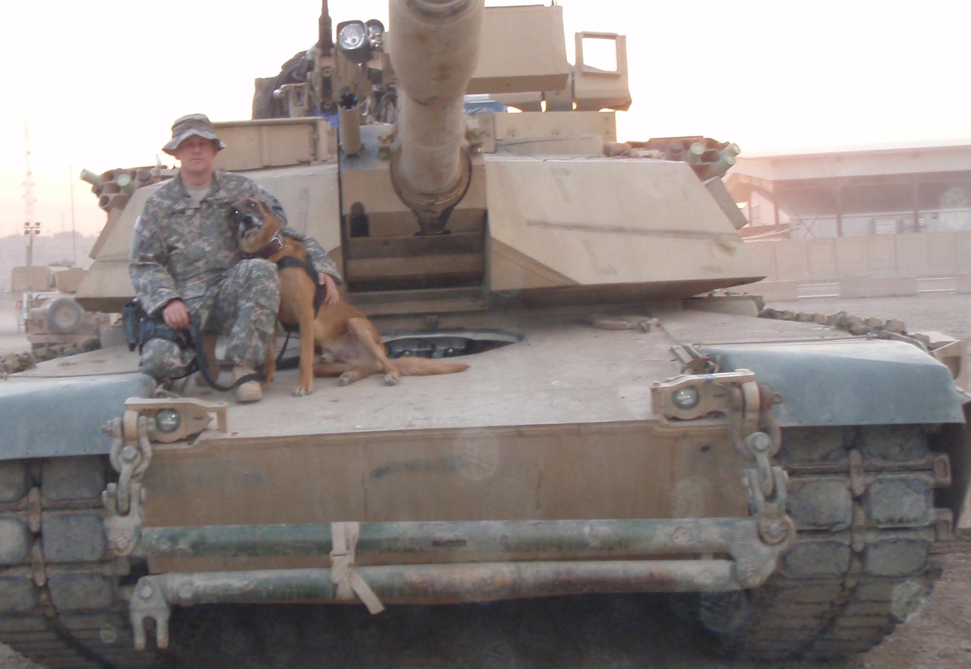 CAMP VICTORY, Iraq – Staff Sgt. Bobby Busha, Multinational Corps – Iraq
military working dog handler deployed from the 92nd Security Forces Squadron at Fairchild, sits with Lucky, his military working dog on an Abrams tank. Sergeant Busha and Lucky conduct patrols with the Army, improvised explosive device sweeps and vehicle sweeps overseas. (Courtesy photo)