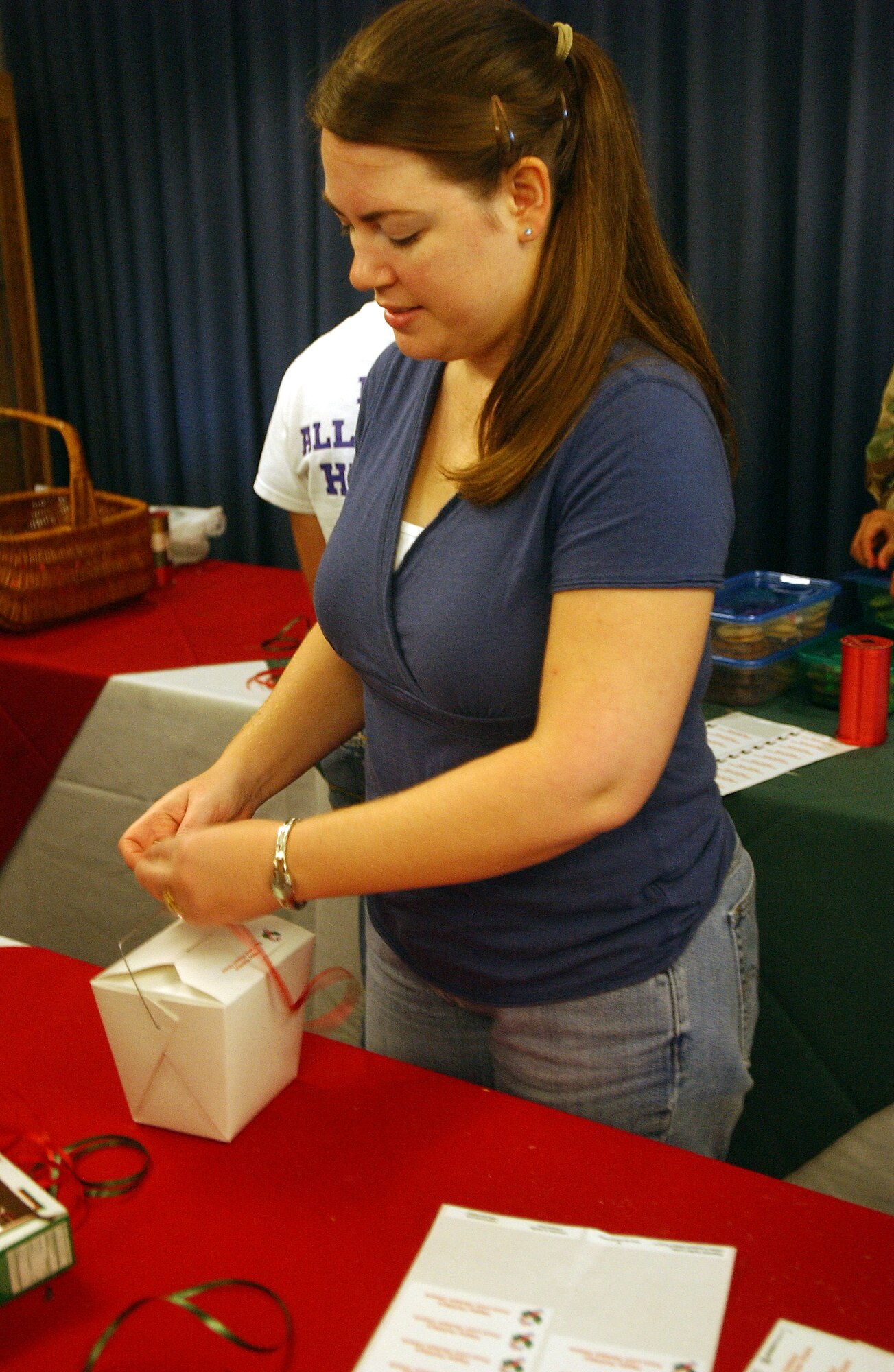 Penny Stegall ties the ribbon and  attaches gift tags to cookie boxes, as part of the Cookie Caper initiative, Dec. 6 at the Officer's Club. More than 20 volunteers pulled together to provide about 1,000 dozen cookies for delivery to Hickam AFB units, Airmen in the dorms and deployed Airmen. Photo by Staff Sgt. Erin Smith