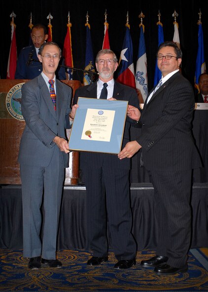 Dr. David S.C. Chu (left to right) presents Ronald B. Greenfield with the Outstanding Defense Department Employee with Disabilities Award as Dr. Joseph M. Guzman assists Dec. 4 in Bethesda, Md. Mr. Chu is the undersecretary of defense for personnel and readiness. Mr. Greenfield is the chief of staff for the 24th Special Tactics Squadron at Pope Air Force Base, N.C. Mr. Guzman is the deputy assistant secretary for strategic diversity integration in the Office of the Assistant Secretary of the Air Force for manpower and Reserve affairs. Mr. Guzman also received the DOD organizational disability award presented to the Department of the Air Force. The purpose of the annual ceremony is to increase the awareness of the contributions to national security made by those working in the system with mental and physical disabilities.  (DOD photo/Fred W. Baker III )