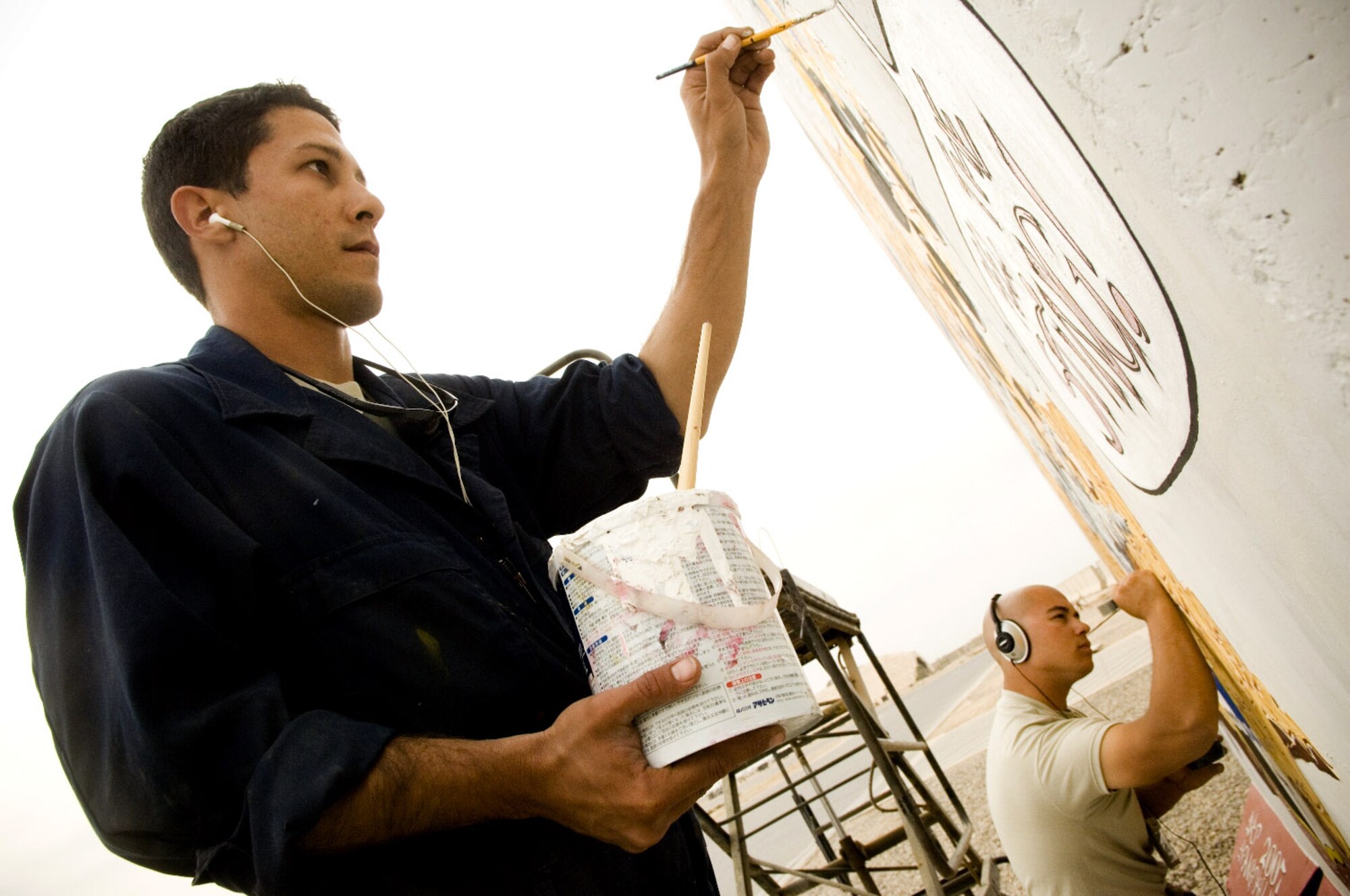 Airmen 1st Class Francisco Coraliz and Andre Cotan add details Dec. 1 on a mural they are painting on the flightline at Balad Air Base, Iraq. Following approved guidelines, deployed members are encouraged to paint legacy murals to build unit morale. Airmen Cotan and Coraliz are with the 322nd Expeditionary Aircraft Maintenance Squadron and deployed from Spangdahlem Air Base, Germany. (U.S. Air Force photo/Staff Sgt. Travis Edwards) 