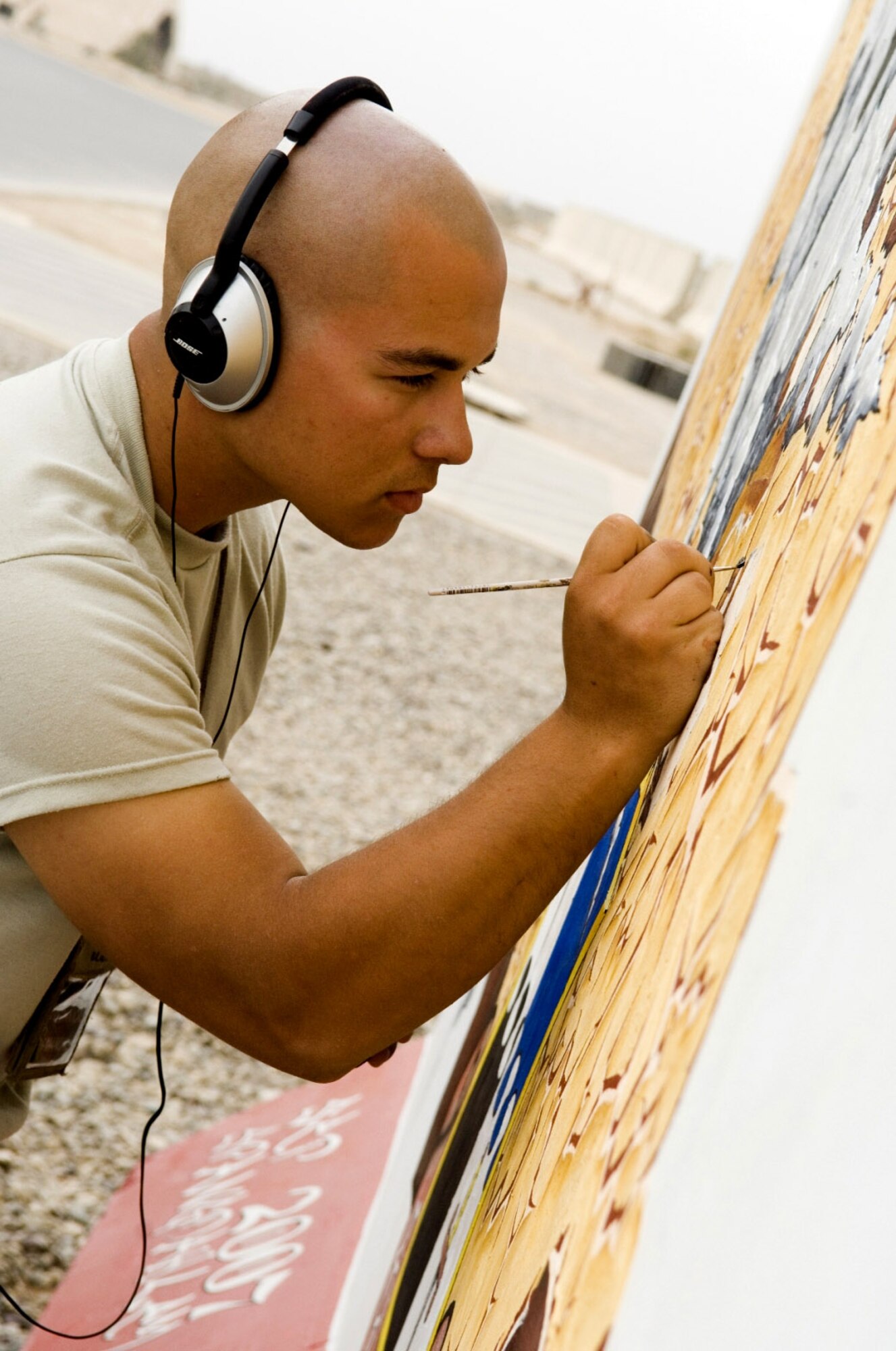 Airman 1st Class Andre Cotan, 322nd Expeditionary Aircraft Maintenance Squadron, adds detail on a mural he is helping create to leave a legacy of art here. Following approved guidelines, deployed members are encouraged to paint to build unit morale. Airman Cotan is deployed from Spangdahlem Air Force Base, Germany. (U.S. Air Force photo/Staff Sgt. Travis Edwards)