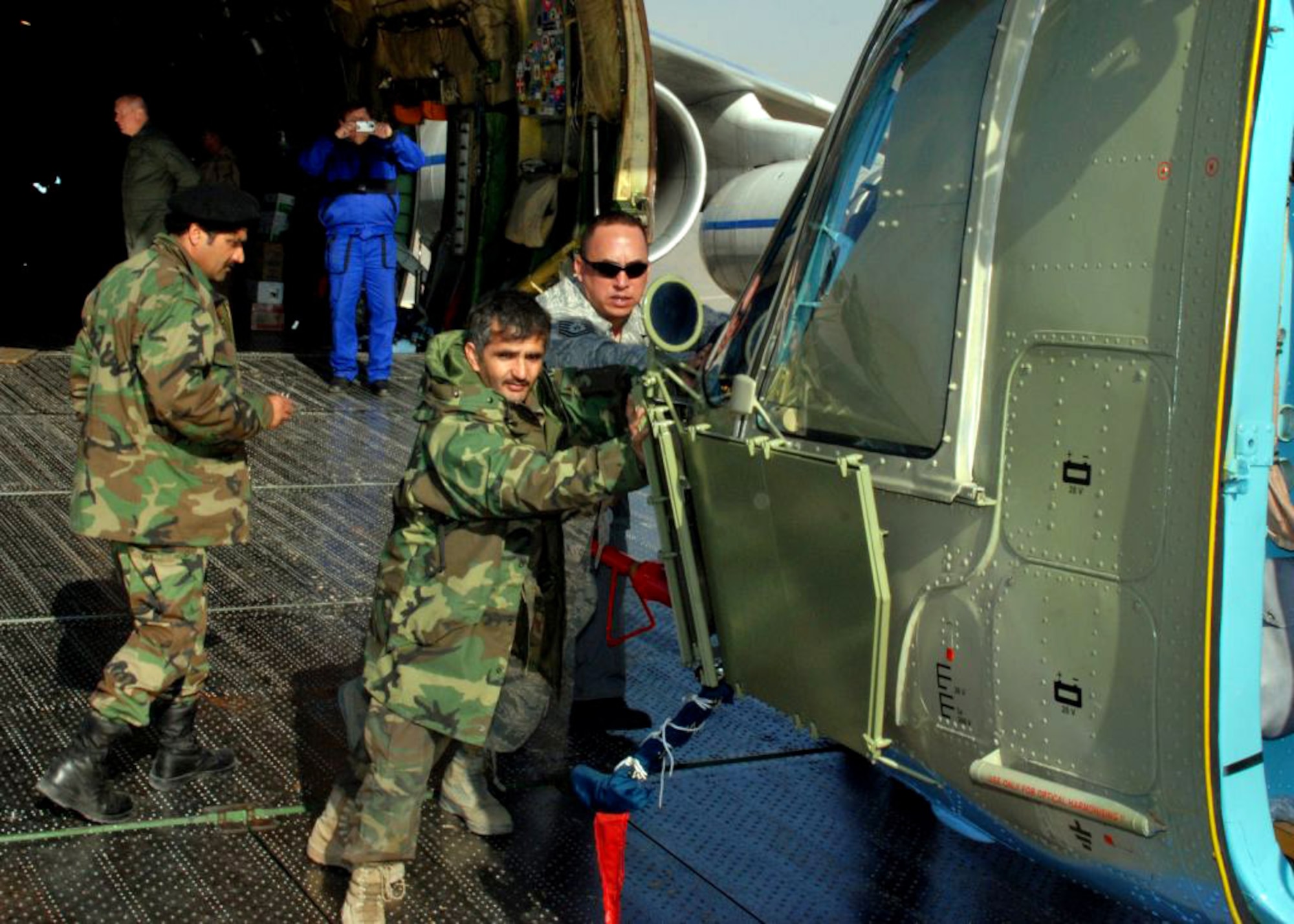 Tech Sgt. John Noa helps an Afghan national army air corps soldier unload a refurbished MI-17 helicopter from an Antonov 124 cargo plane Dec. 5 at Kabul, Afghanistan. The helicopter was being delivered to the Afghan national army air corps from the Czech Republic. (U.S. Navy photo/Petty Officer 1st Class David M. Votroubek) 
