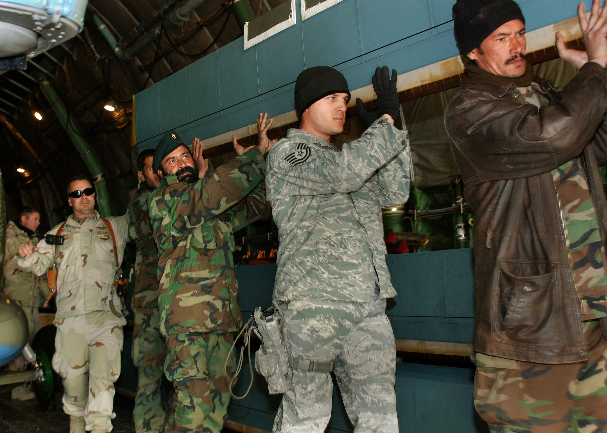 Tech. Sgt. Scott Hirschenberger helps Afghan national army air corps helicopter crew chiefs unload helicopter blades from a cargo plane Dec. 5 at Kabul, Afghanistan. The blades are part of a shipment of three refurbished MI-17 helicopters donated to the ANAAC by the Czech Republic. Sergeant Hirschenberger is a mentor from the Combined Security Transition Command-Afghanistan and teaches the Afghan soldiers proper safety procedures, aircraft handling and maintenance. (U.S. Navy photo/Petty Officer 1st Class David M. Votroubek)
