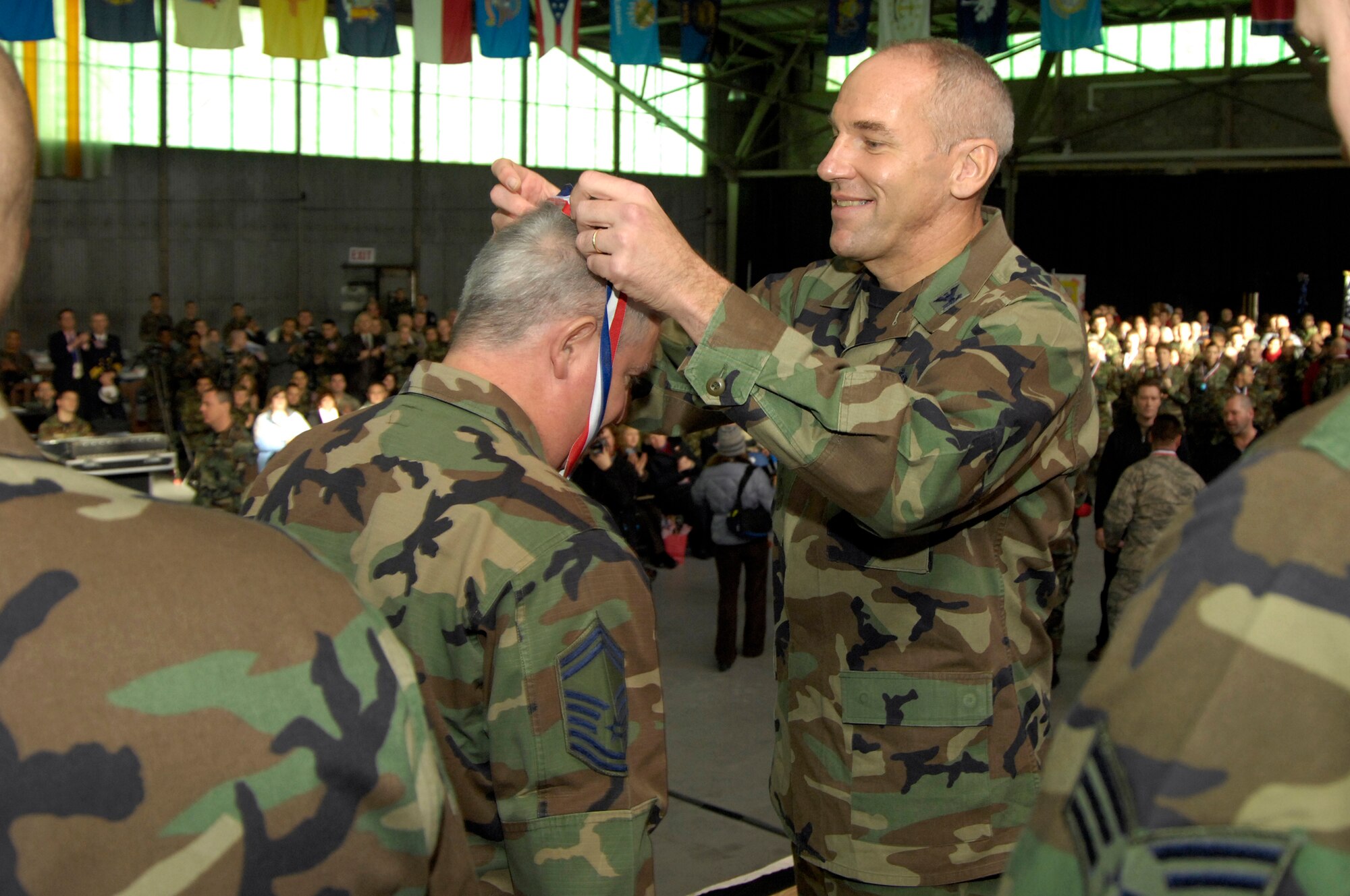 HANSCOM AFB, Mass. -- Col. Tom Schluckebier, 66th Air Base Wing commander, places a ‘heroes’ medallion around the neck of Air Force Reserve Senior Master Sgt. Steven Meltzer, 85th Aerial Port Squadron, during a homecoming celebration at Hanscom Dec. 5. Forty-two personnel assigned to the base returned from deployments during the past six months and were honored along with their families during the Heroes’ Homecoming event. (U.S. Air Force photo by Mark Wyatt)