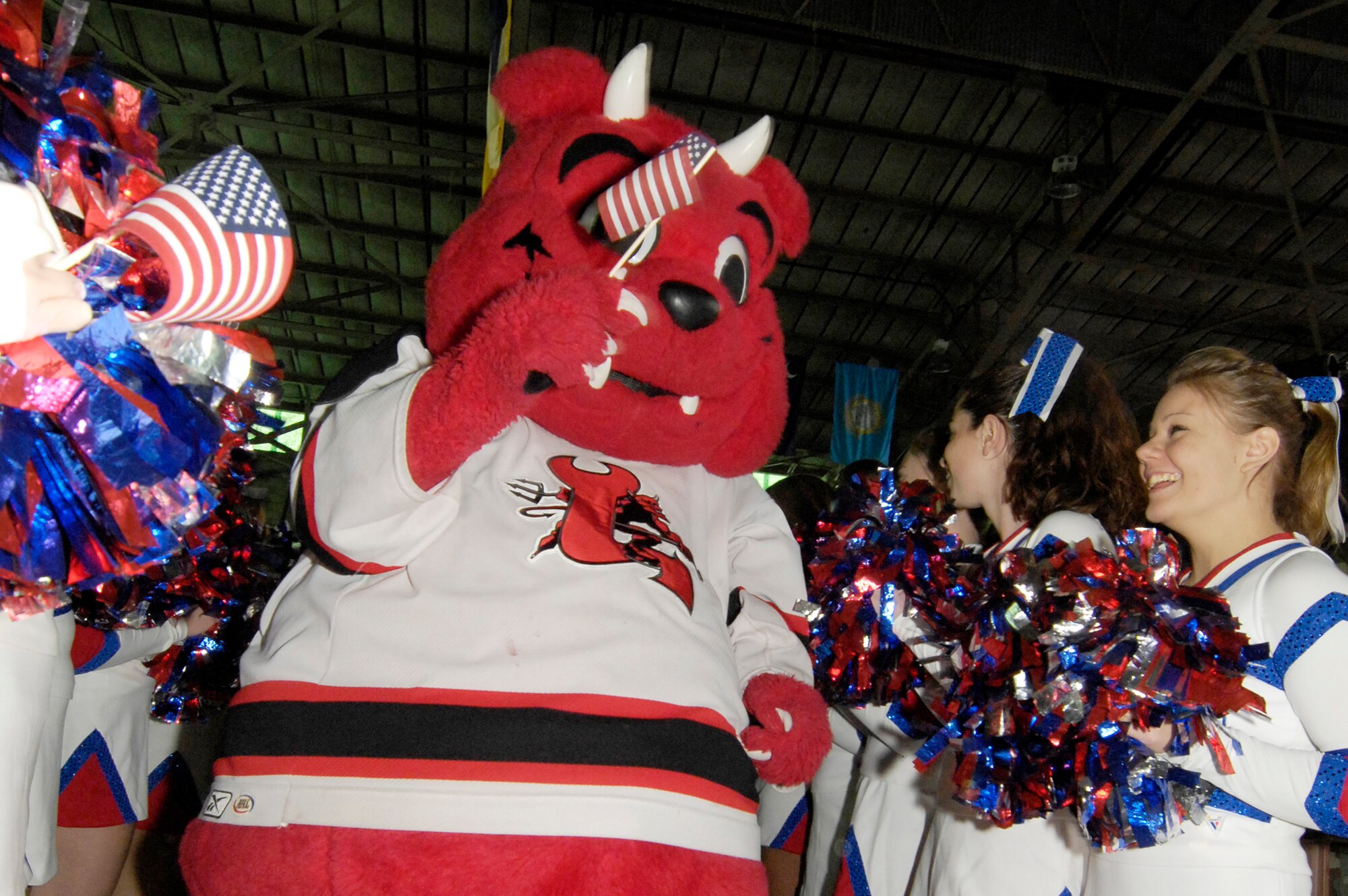 HANSCOM AFB, Mass. -- The Lowell Devils hockey team mascot, Devil Dog, leads a group of recently returned Hanscom deployers through a group of cheerleaders from Burlington High School, Mass., during the base’s celebration to honor the efforts of the deployed Airmen and their families Dec. 5. (U.S. Air Force photo by Mark Wyatt)