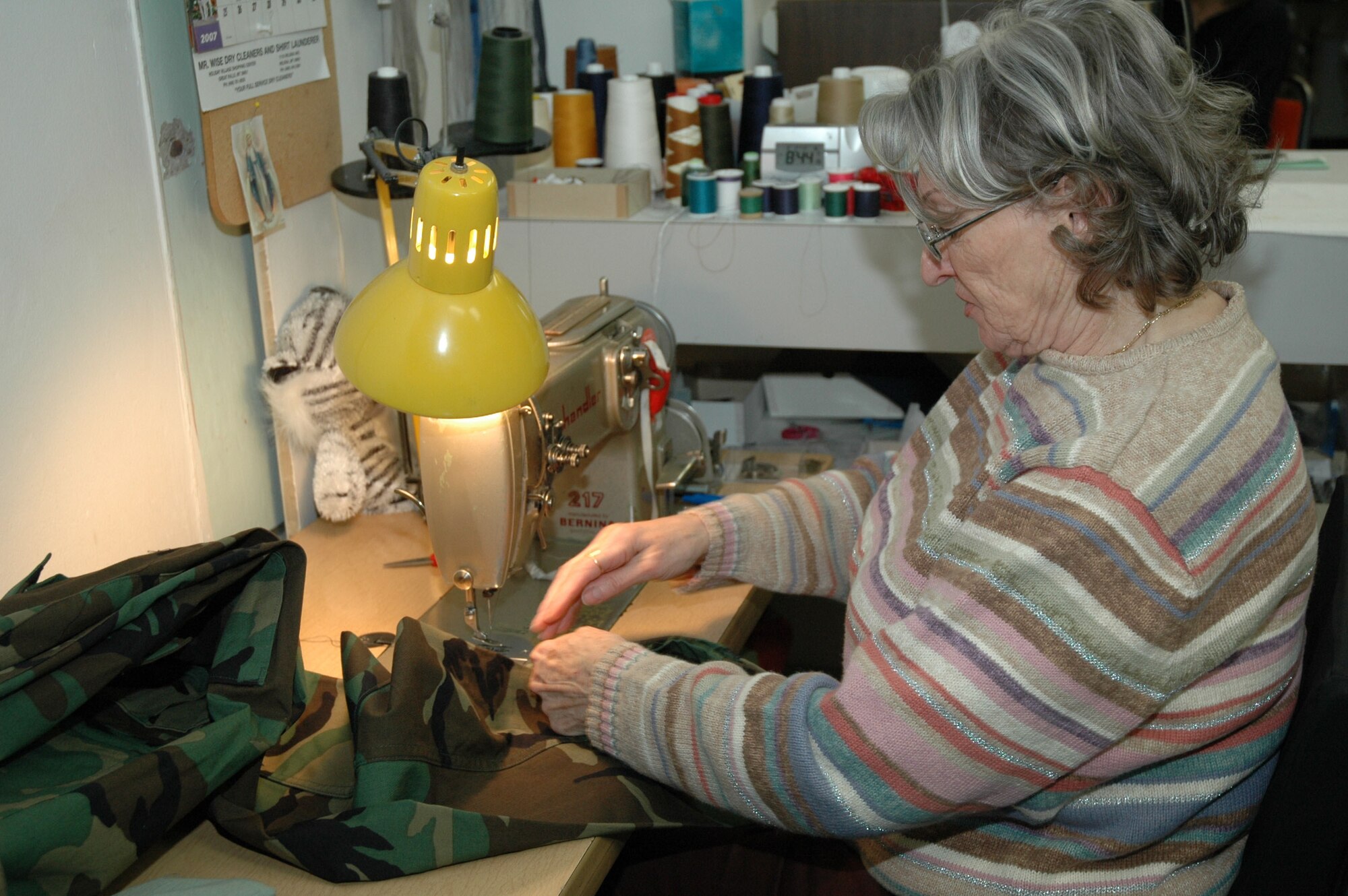 Ms. Harris gets her sewing machine ready before working on a pair of battle dress uniform pants. Ms. Harris learned to sew at the age of 5 on her grandmother's farm in France, and has been an employee at Malmstrom for 17 years. (U.S. Air Force photo/Valerie Mullett)