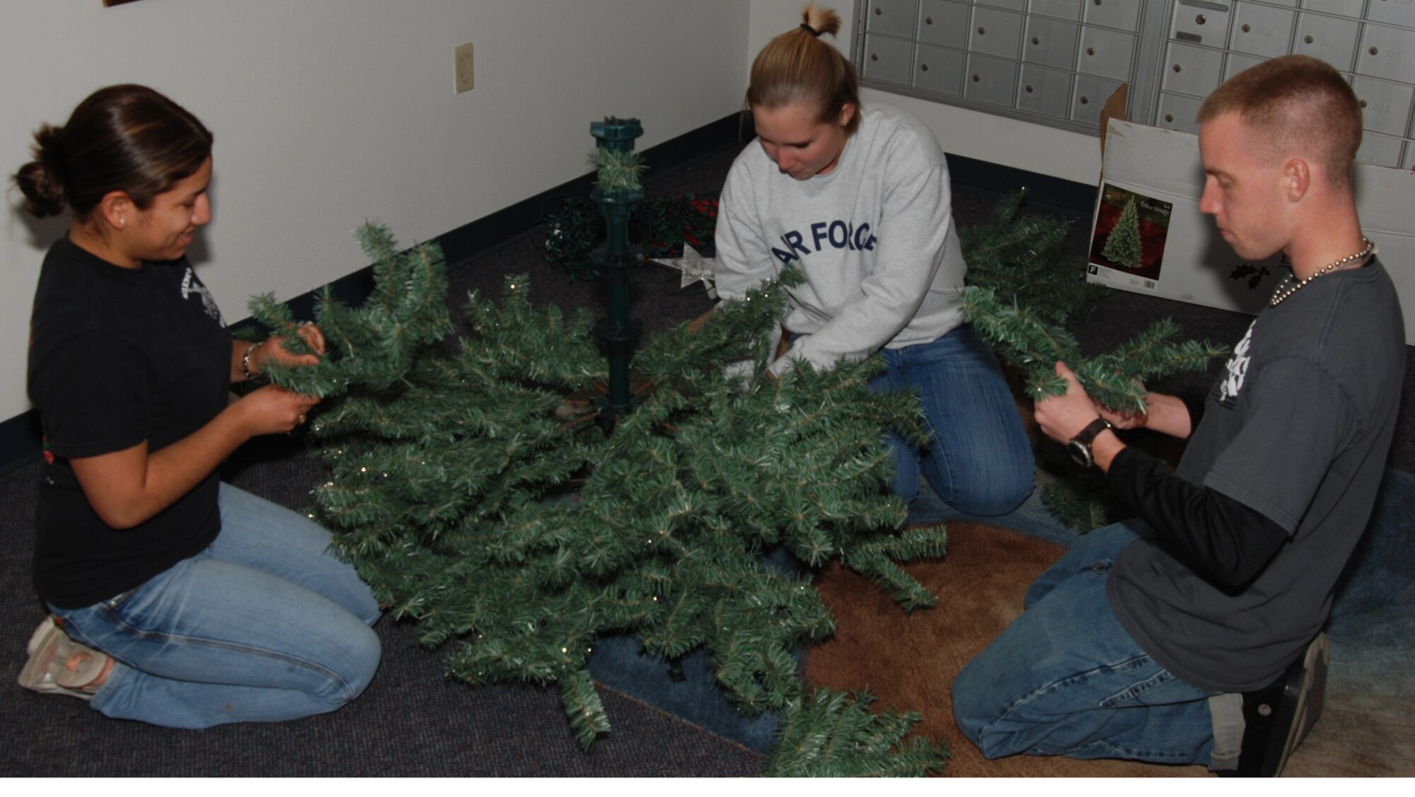 MCCONNELL AIR FORCE BASE, Kan. – Airman Anaid Nieto and Airman 1st Class Melissa Oja, 22nd Operation Support Squadron and Airman 1st Class Lucas Treat, 350th Air Refueling Squadron piece together a holiday tree to decorate dorm 340, Nov. 22. (photo by Airman 1st Class Jessica Lockoski)