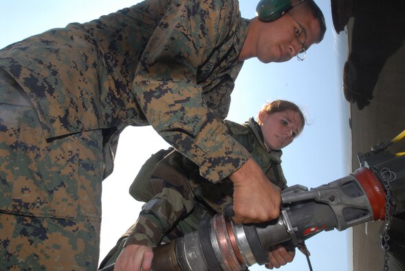 Lance Corporal Micha Martinez, MSWW 171, and Airman 1st Class Christina Flake, 18th Logistic Readiness Squadron, use a bottom loader to pump fuel into the fuel tanks of a R-11 fuel truck at Kadena Air Base, Japan, Dec. 6. Airmen from the 18th Wing joined with elements from the 1st Marine Aircraft Wing to conduct a joint operational readiness exercise here Dec. 3-7. (U.S. Air Force/Senior Airman Darnell T. Cannady)