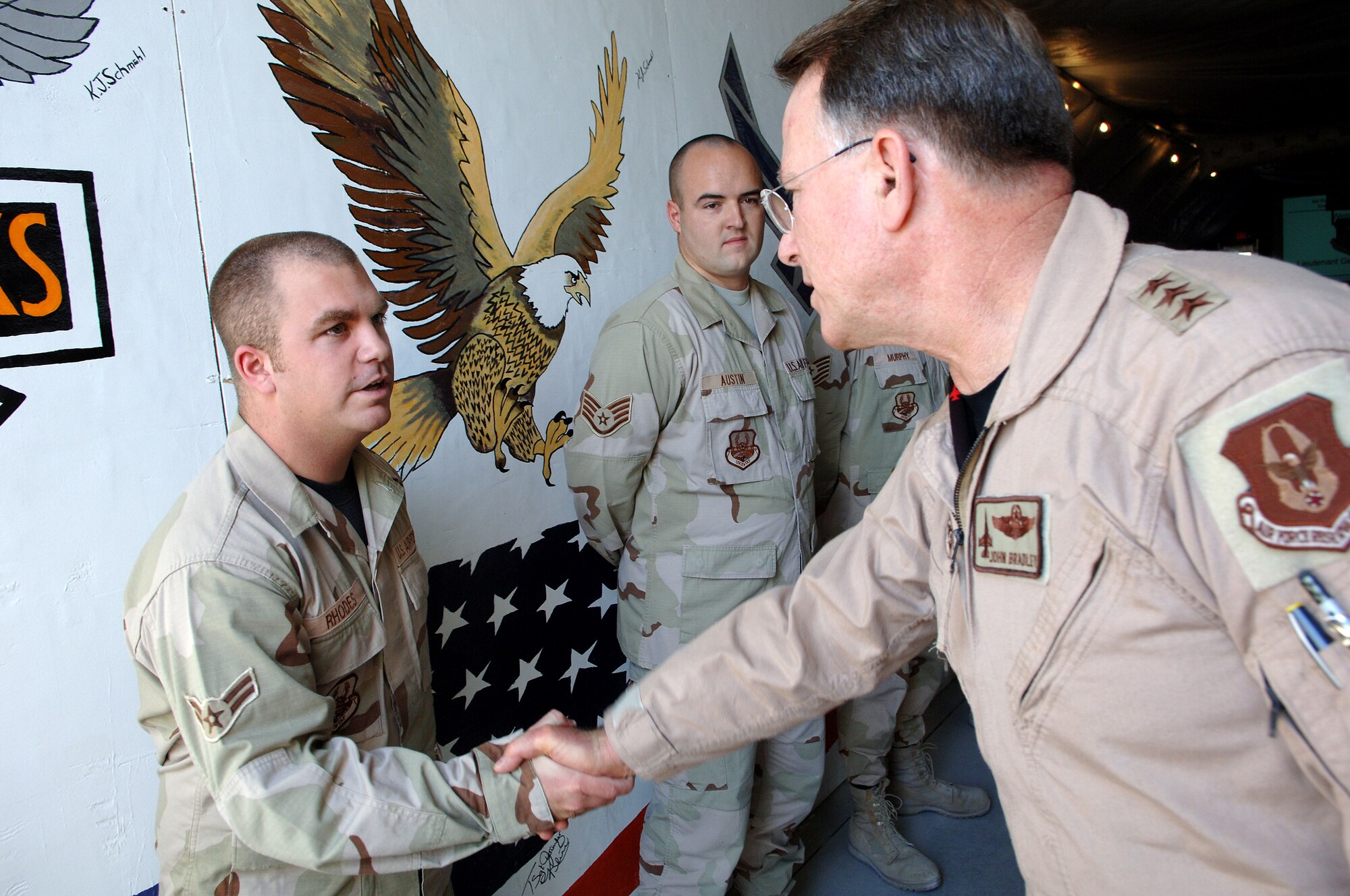 SOUTHWEST ASIA - Lt. Gen. John Bradley, Air Force Reserve Center commander, shakes hands with Airman 1st Class Nicholas Rhodes, 379th Expeditionary Logistics Readiness Squadron, while Staff Sgt. Nathan Austin, 379th ELRS looks on. The general was touring facilites at a base in Southwest Asia recently. Airman Rhodes is deployed from McConnell AFB, Kan., and Sergeant Austin is deployed from Travis AFB, Calif. (U.S. Air Force Photo/Master Sgt. Greg Kunkle)