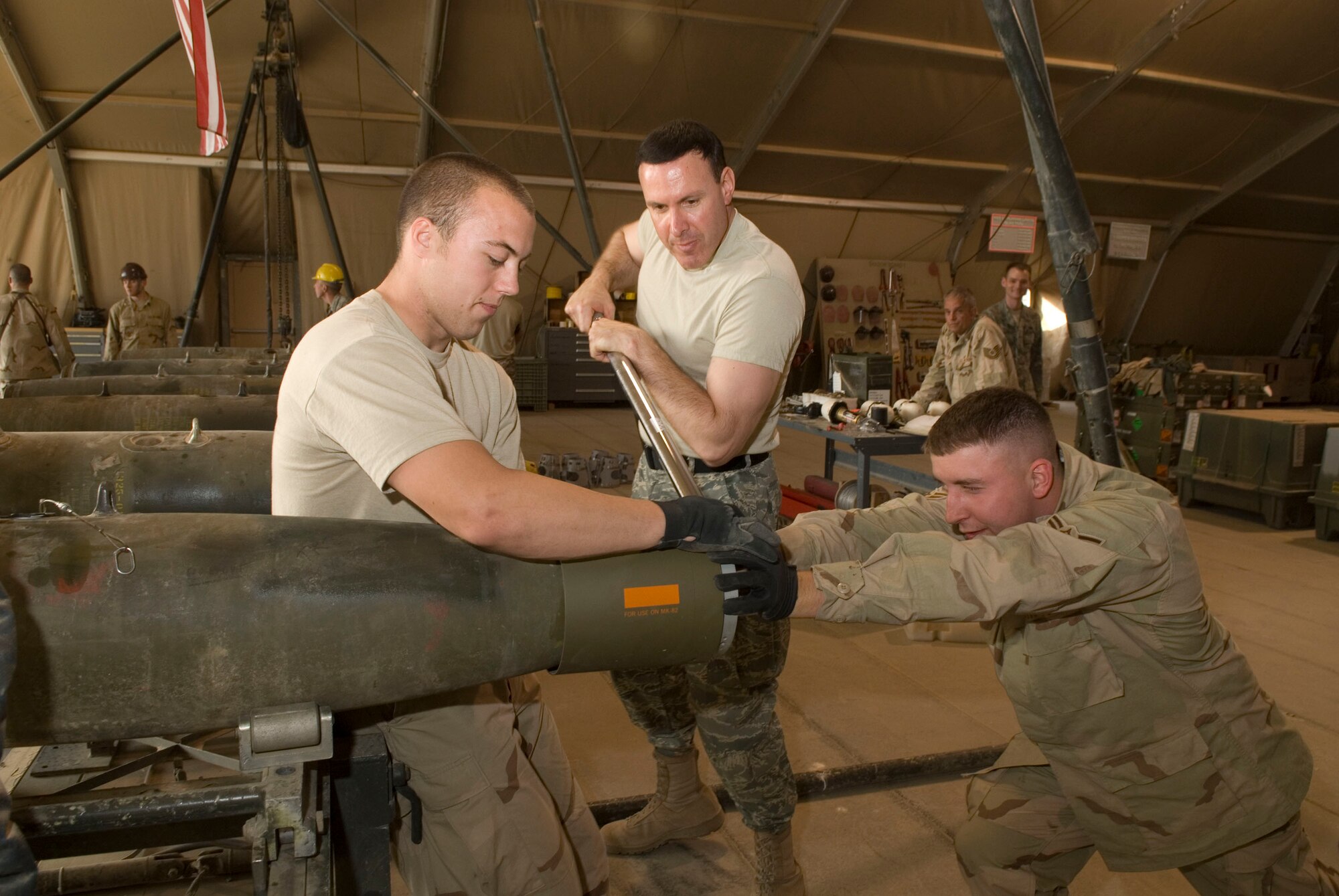 BALAD AIR BASE, Iraq -- Airmen 1st Class Bradley Martin and Joseph Dunlavey, 332nd Expeditionary Maintenance Squadron, help Col. Steven Shepro, 332nd Air Expeditionary Wing vice commander, connect a fin kit collar to the nose of a bomb body  here, Dec. 5. Wing leaders worked alongside the Airmen as they built bombs for future combat operations. Airmen Martin and Dunlavey are deployed from Spangdahlem Air Base, Germany and Colonel Shepro is deployed from Pope Air Force Base, N.C. (U.S. Air Force photo/Staff Sgt. Joshua Garcia)