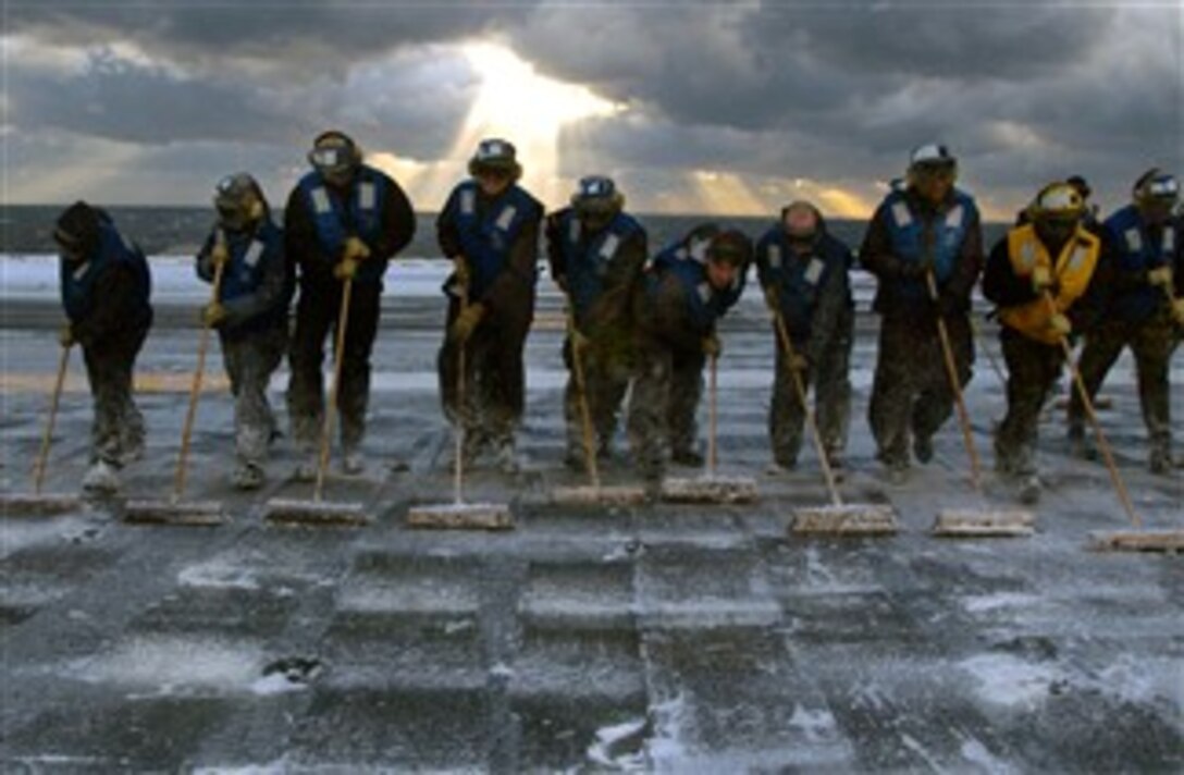 U.S. Navy flight deck personnel perform a scrubbing exercise during a counter measure wash down of aqueous film forming foam on the flight deck of USS Theodore Roosevelt, Dec. 4, 2007. 
