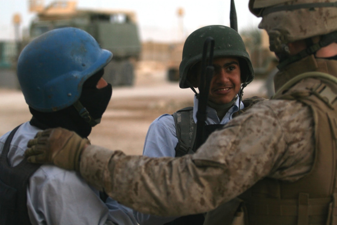 ANAH, Iraq ? A Marine from Company K, 3rd Battalion, 2nd Marine Regiment, Task Force Wolfpack, Regimental Combat Team 2, talks with two Iraqi policemen before a foot patrol through Anah, Iraq. The bond formed between the Marines and Iraqi police has grown to a point where each has found a newfound respect for each other while striving together for the same cause.