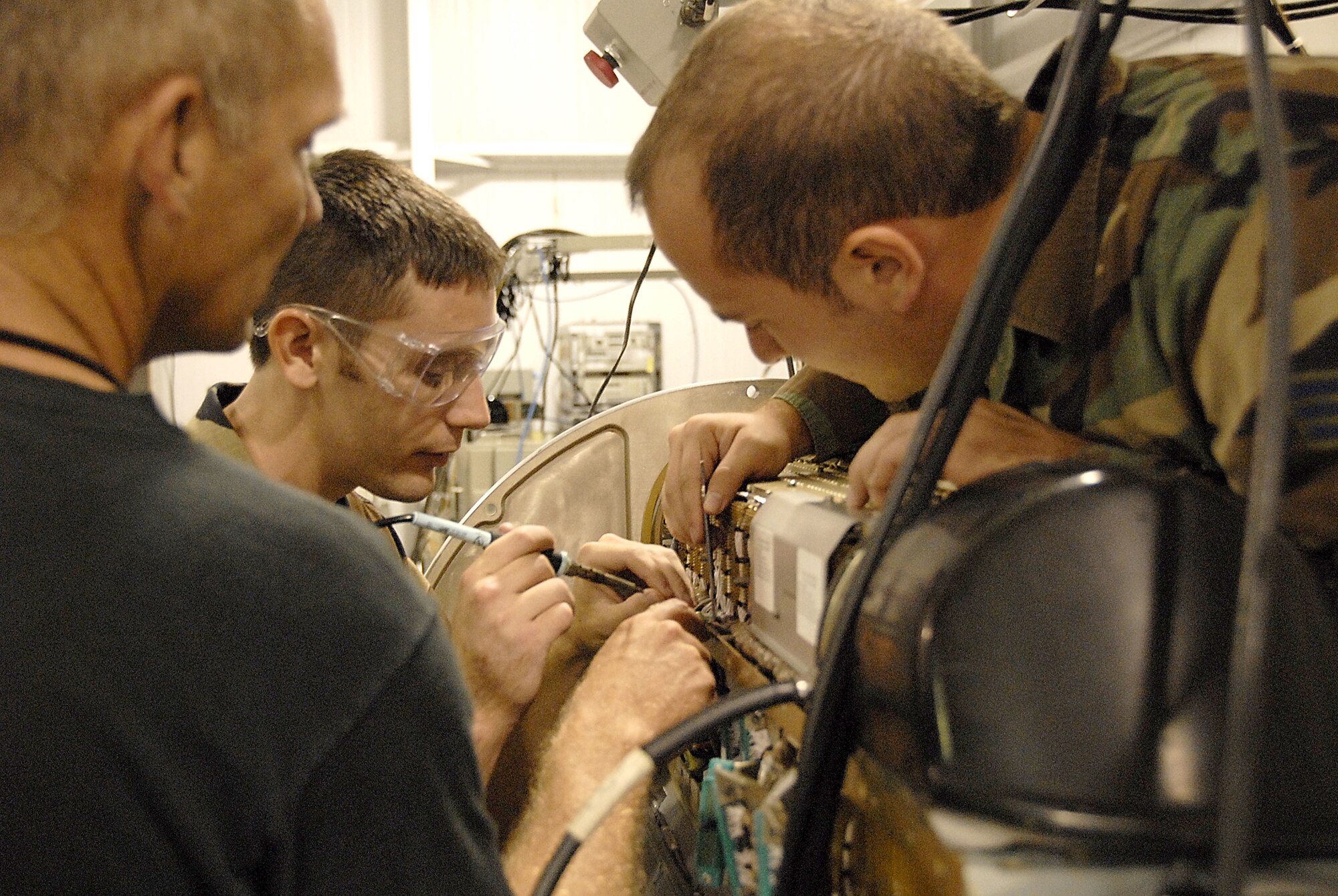 Tech. Sgt. Harold Blunt (left) supervises Senior Airman Adam Dryden's work as he solders a damaged back plate assembly on one of the wing's AN/ALQ-184 Electronic Counter Measure (ECM) Attack pods. Senior Airman Adam Riegle (right) assists in the procedure. The Airmen are reservists with the 442nd Fighter Wing, an A-10 Thunderbolt II unit at Whiteman AFB, Mo. (US Air Force photo/Master Sgt. Bill Huntington)