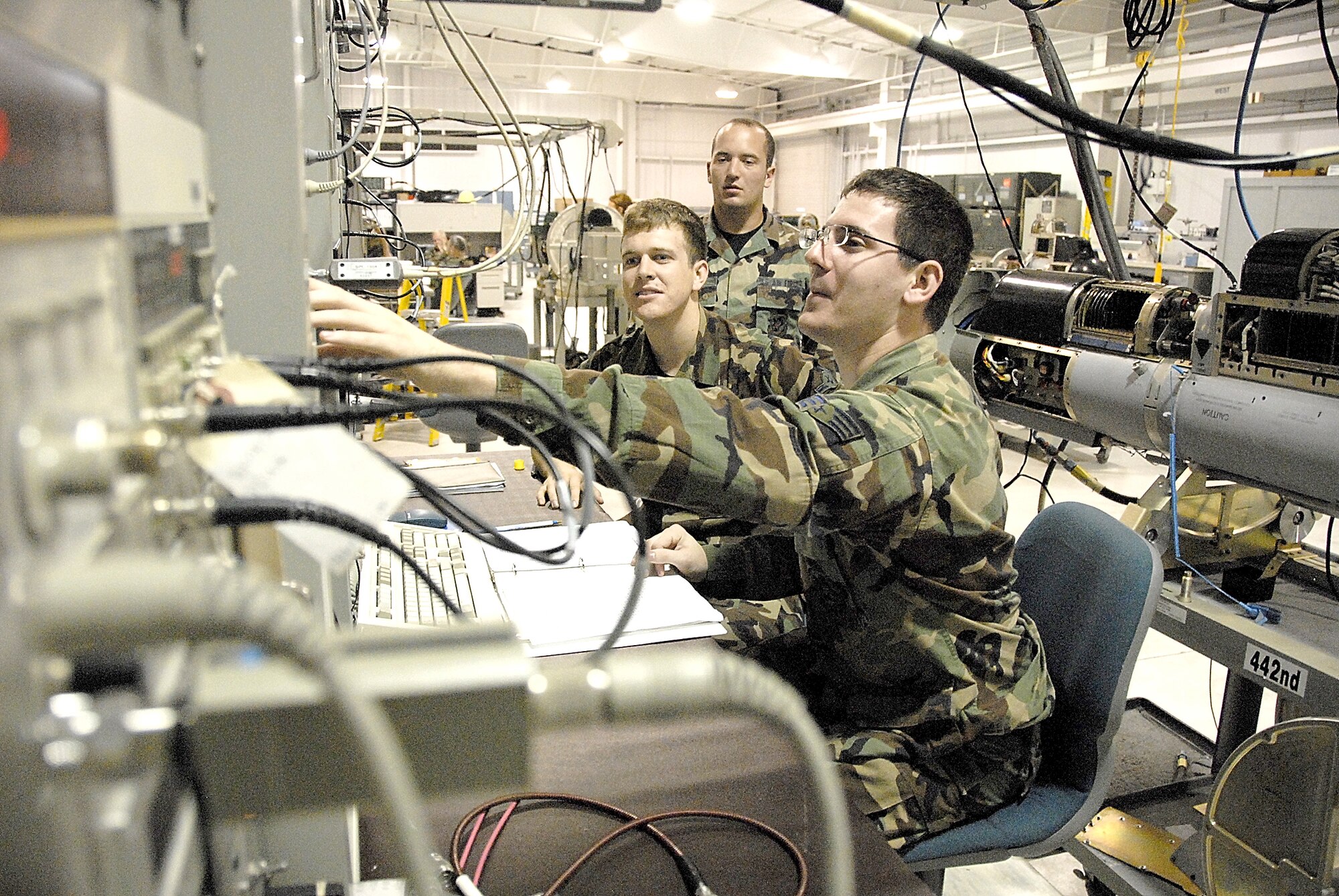 Airman Geoffrey From (left) and Senior Airman Sean Hargis perform a 30-day periodic maintenance inspection on the Electronic Warfare Pod Shop's ALM-233D electronic countermeasures pod mockup while in the background Senior Airman Adam Riegle observes their work. The Airmen are reservists with the 442nd Fighter Wing, an A-10 Thunderbolt II unit at Whiteman AFB, Mo. (US Air Force photo/Master Sgt. Bill Huntington)